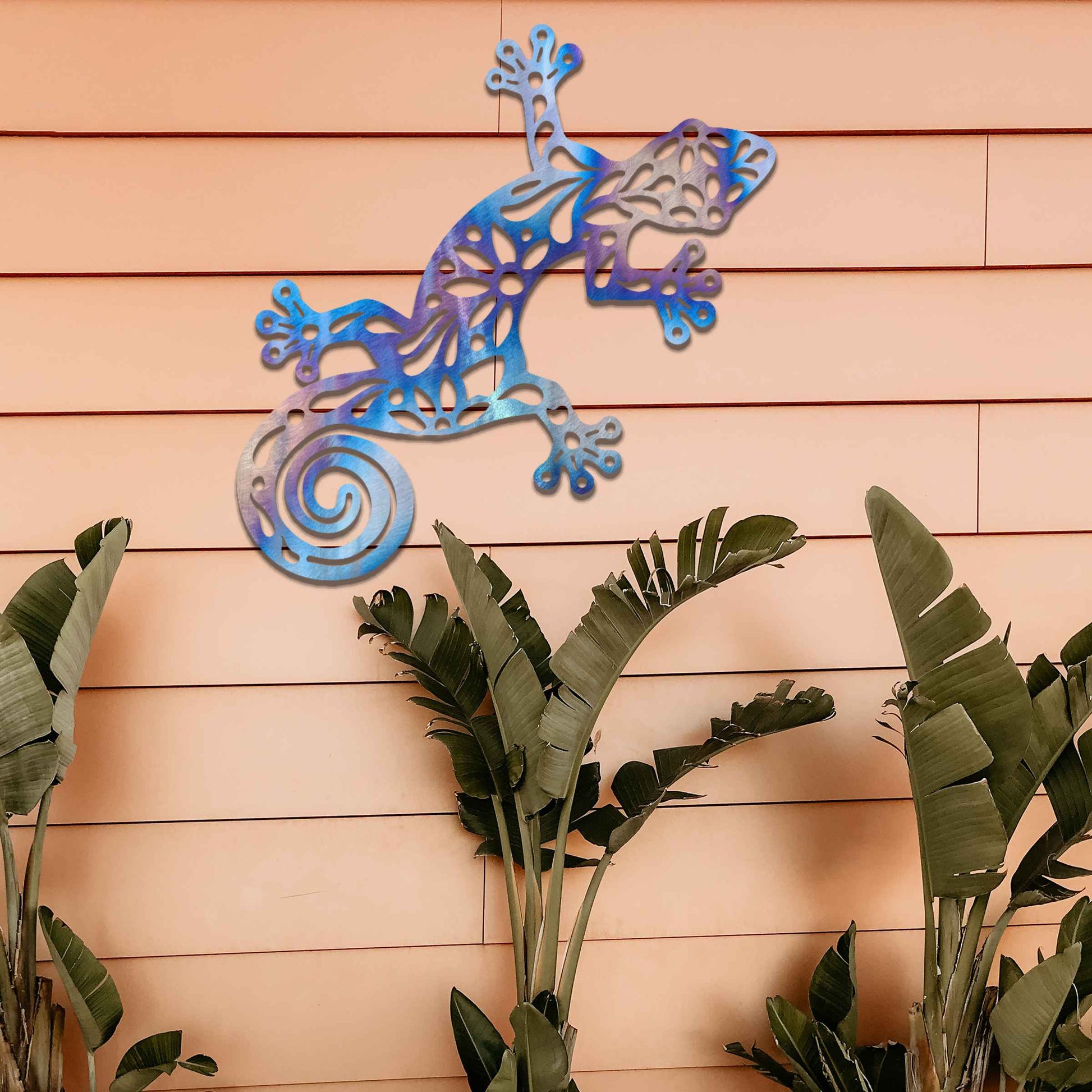 Metal garden decoration featuring a gecko design with floral and spiral cutouts, offering a playful and artistic accent to outdoor walls, seamlessly blending into rustic and natural settings.
