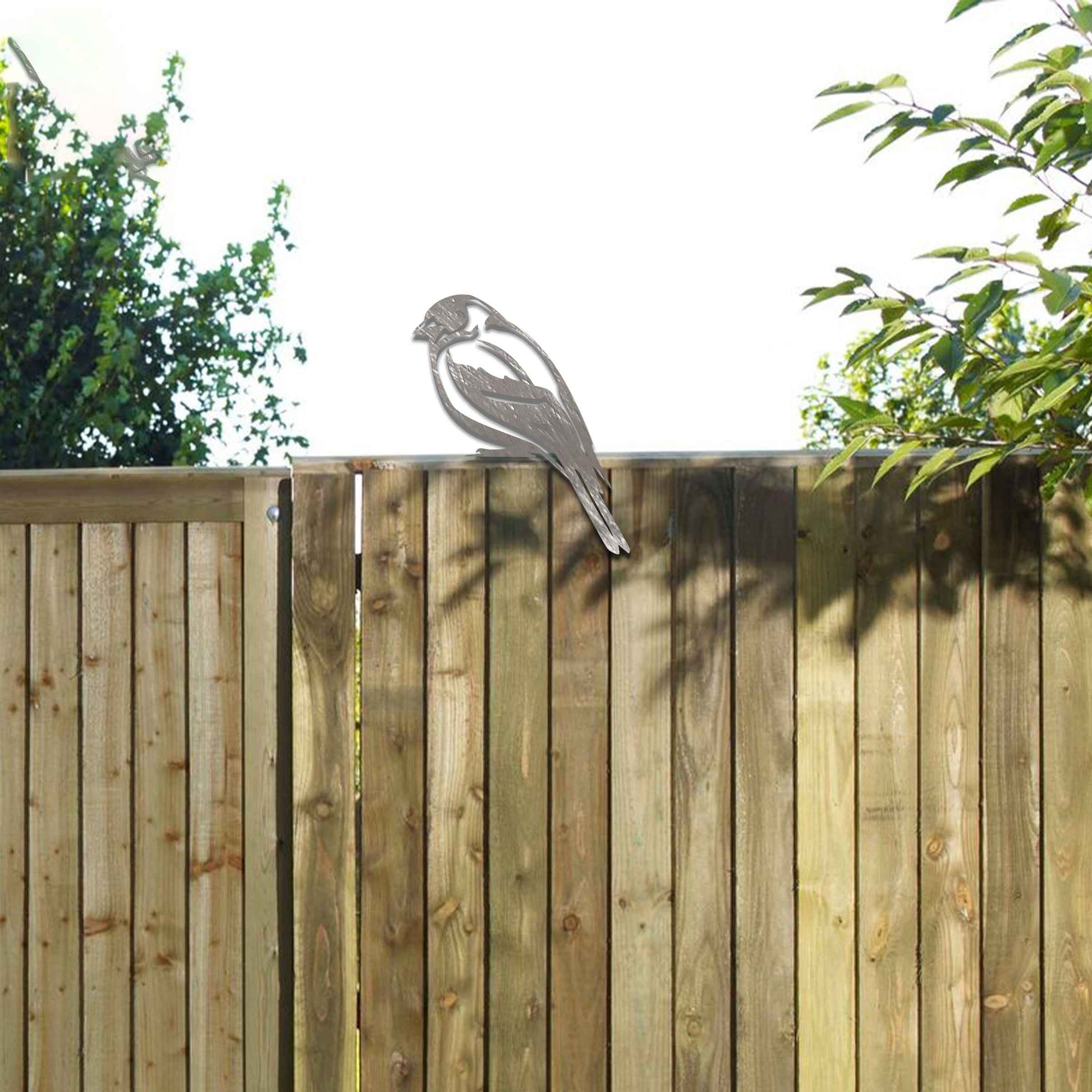 Metal garden decoration featuring a swallow silhouette with intricate cutout details and a rustic finish, designed to perch elegantly on wooden fences, adding a graceful and natural touch to outdoor spaces.
