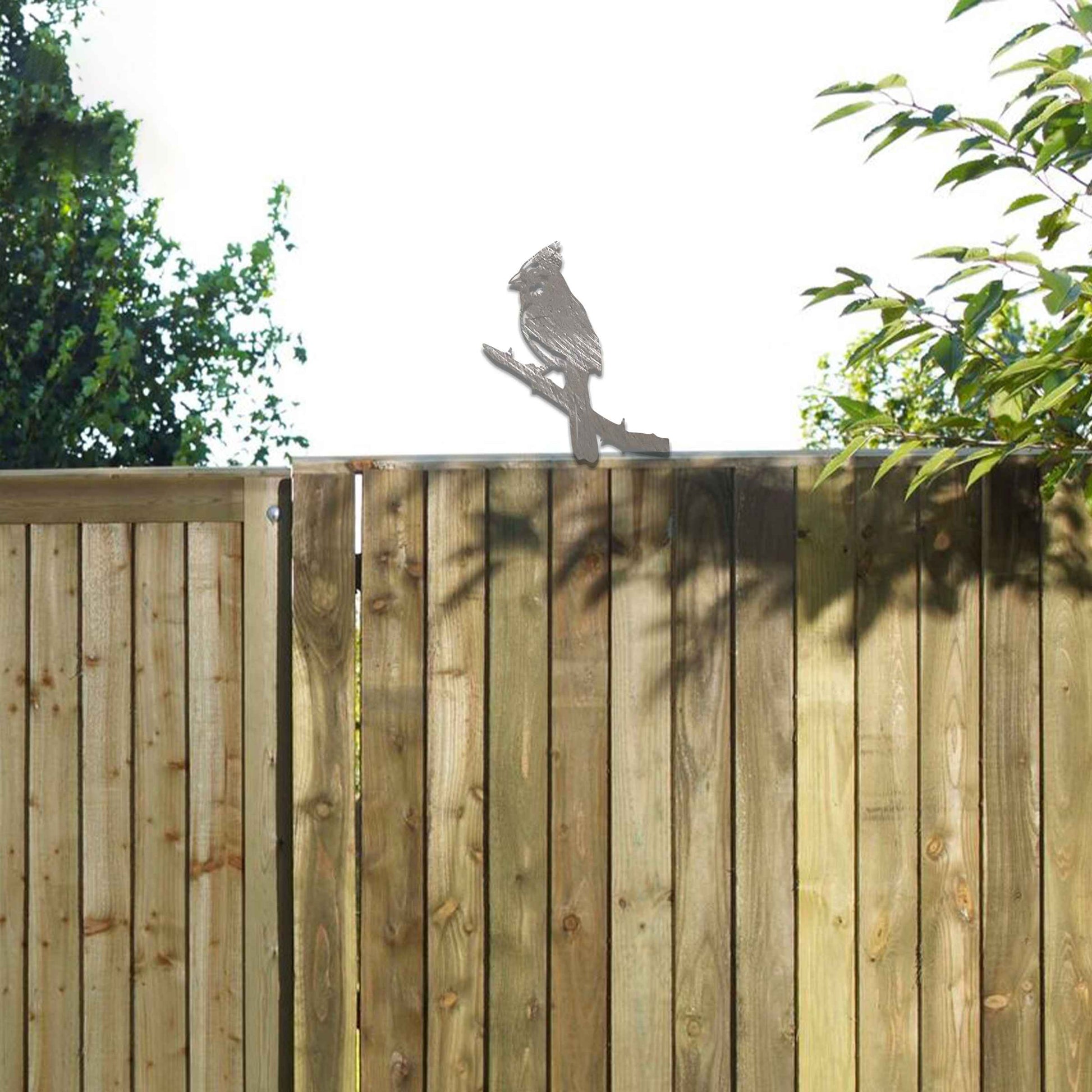 Metal garden decoration featuring a cardinal perched on a branch with intricate cutout details and a rustic finish, designed to enhance wooden fences or gates, adding a striking and natural accent to outdoor spaces.