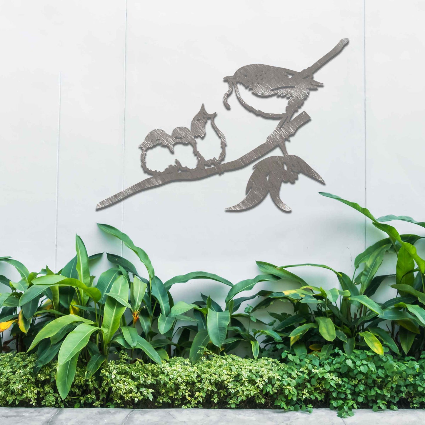 Metal wall art featuring a bird perched on a branch with two smaller birds sitting closely together, crafted in a rustic finish. This piece brings a touch of nature-inspired charm to indoor or outdoor spaces.