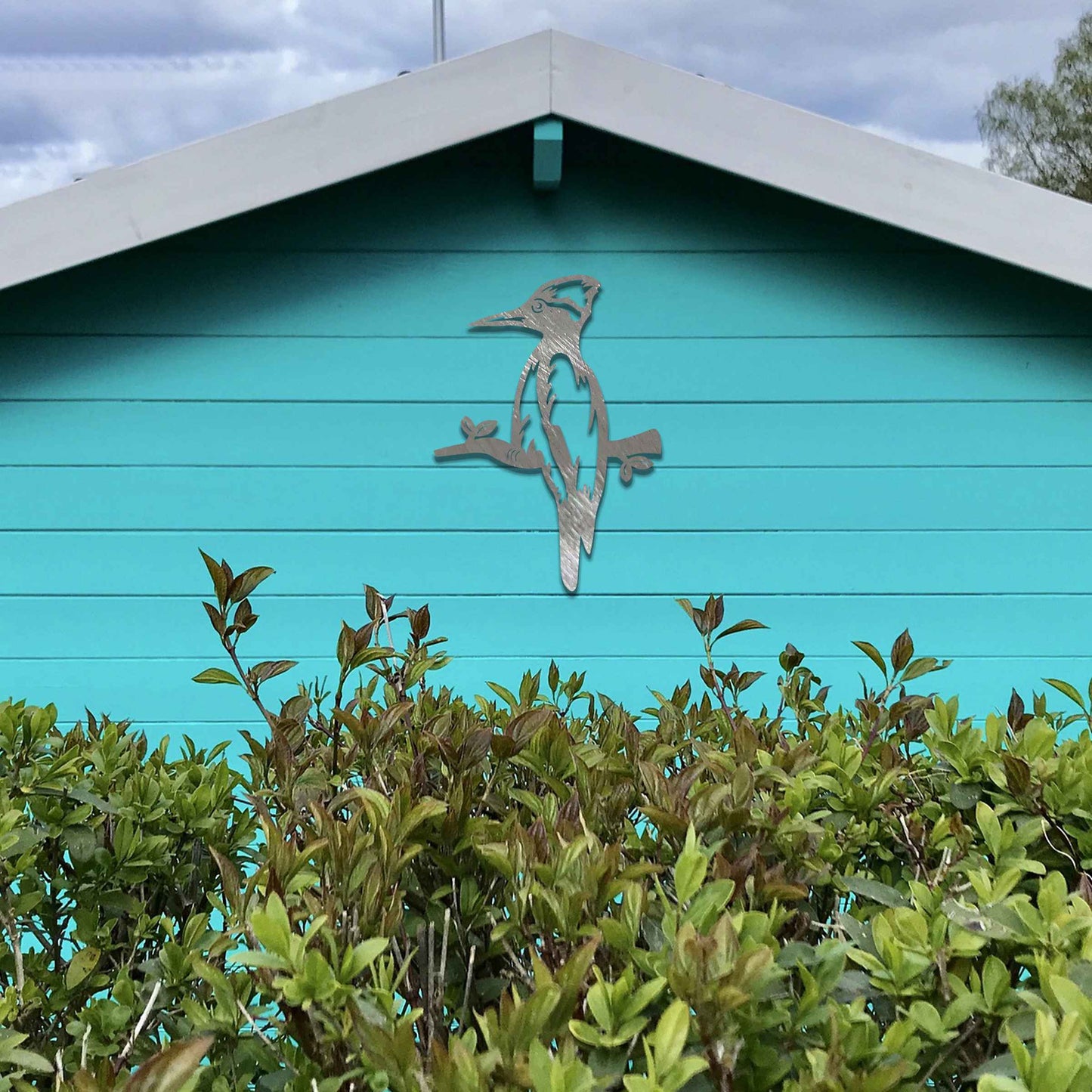 Metal garden decoration featuring a woodpecker perched on a branch, crafted with a rustic finish, adding a touch of nature-inspired charm and elegance to outdoor walls or garden settings.