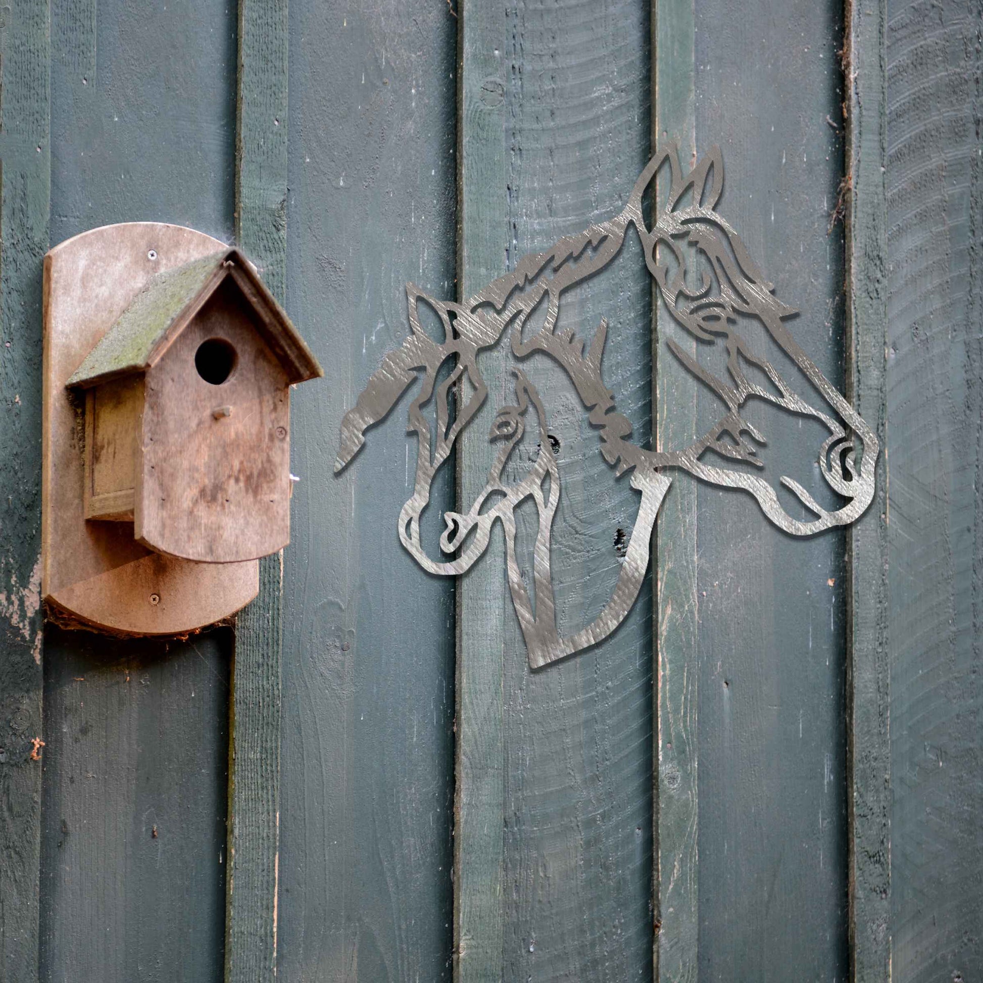 Metal wall art featuring the heads of two horses, one adult and one foal, side by side. The artwork is designed with bold, clean lines, emphasizing the intricate details of the horses' faces.