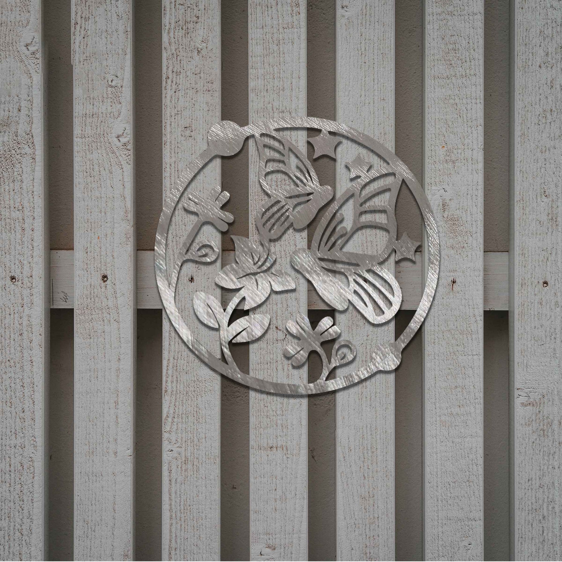 Metal garden decoration featuring a circular design with butterflies, flowers, and stars, crafted with a rustic finish, adding a whimsical and nature-inspired charm to outdoor walls or fences.