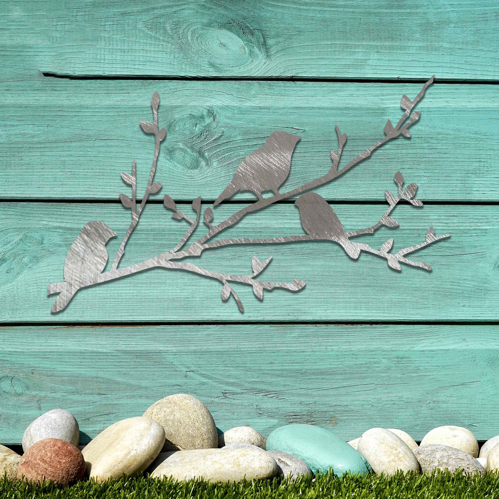 Metal garden decoration featuring three birds perched on a leafy branch, crafted with intricate cutout details and a rustic finish, adding a charming and natural touch to outdoor walls or garden spaces.
