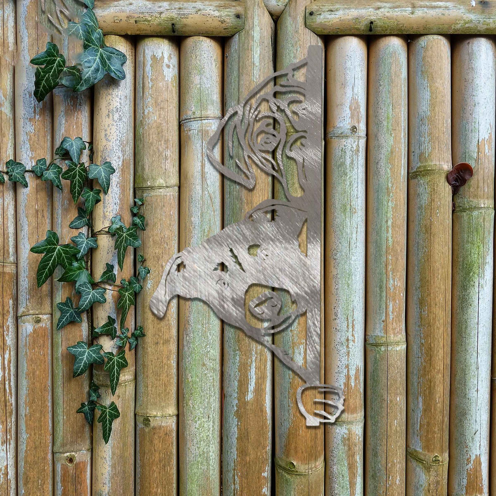 This image features a playful dog peeking through a gate, captured in a rusted finish. Its curious expression brings a whimsical touch to the surroundings, creating an inviting, charming atmosphere for any garden or outdoor space.