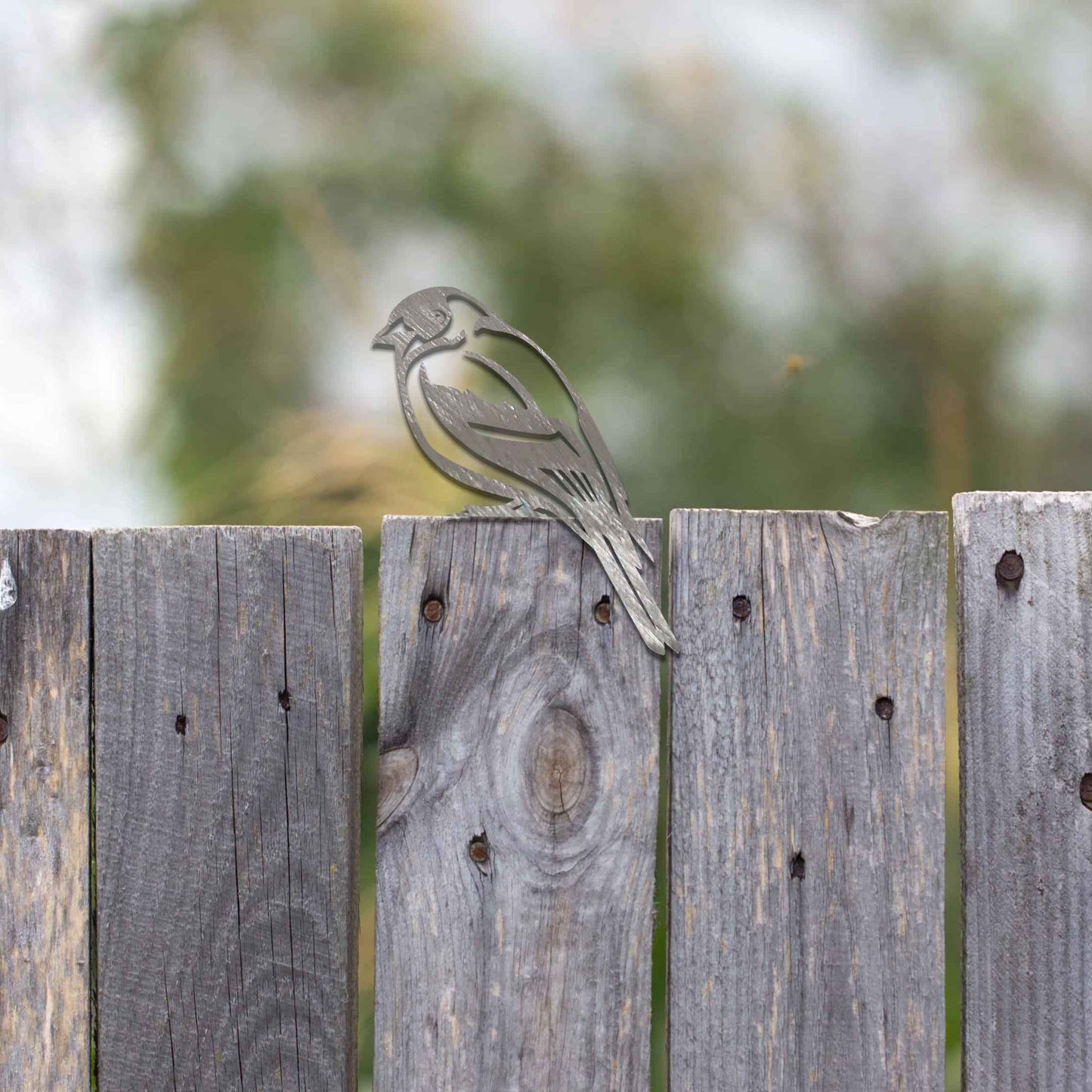 Metal garden decoration featuring a swallow silhouette with intricate cutout details and a rustic finish, designed to perch elegantly on wooden fences, adding a graceful and natural touch to outdoor spaces.
