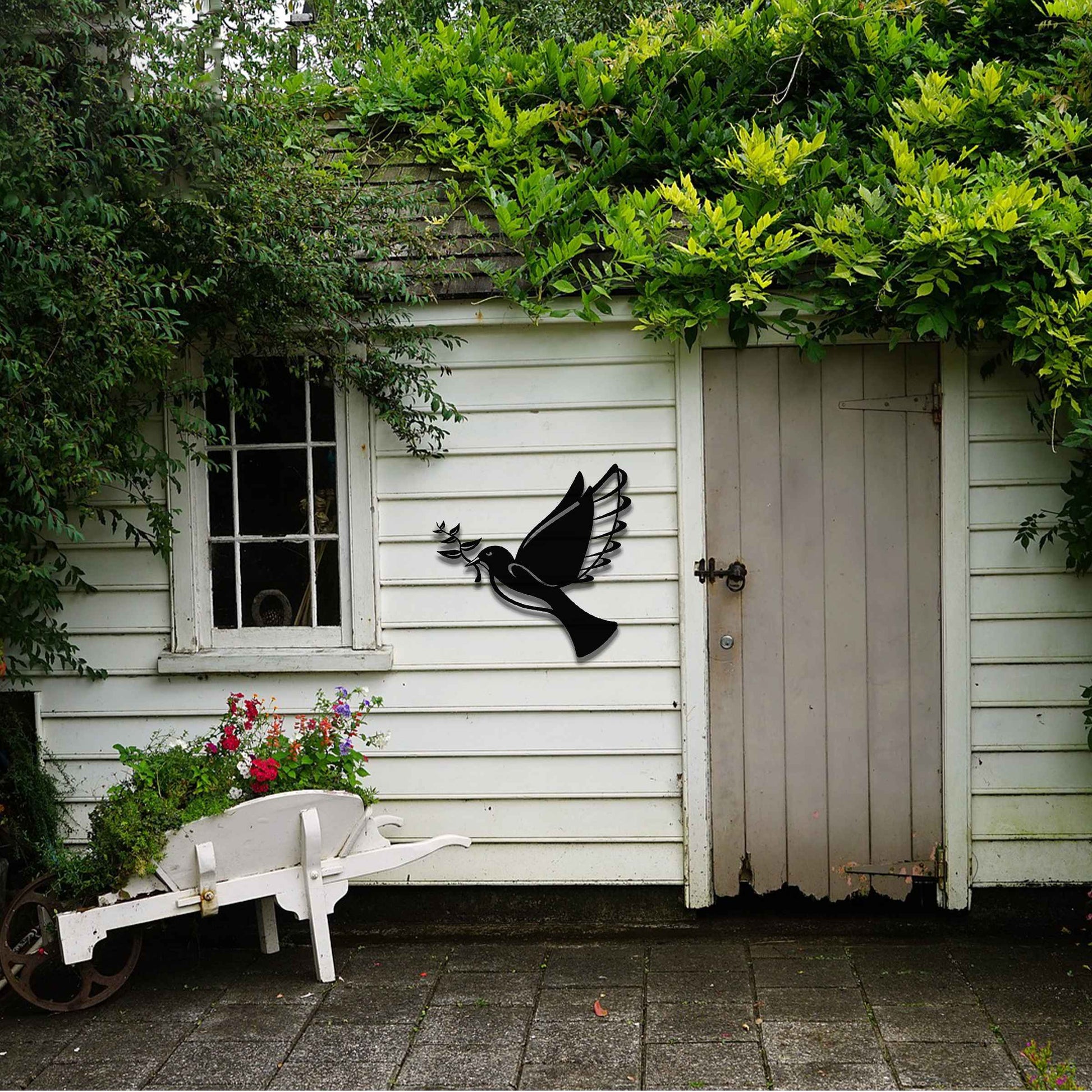 Metal garden decoration featuring a dove in flight holding an olive branch, crafted with a rustic finish, symbolising peace and harmony while adding a touch of elegance and meaning to outdoor spaces.