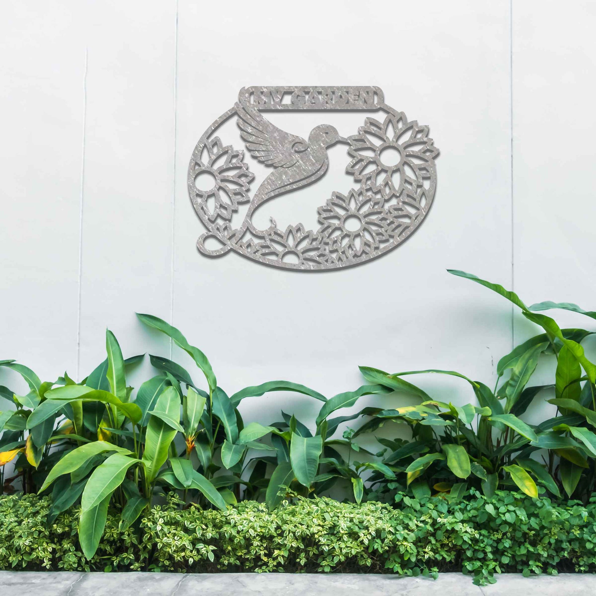 Metal garden decoration featuring a hummingbird surrounded by blooming sunflowers within an oval frame, inscribed with "My Garden," adding a personalised and nature-inspired charm to outdoor walls or fences.