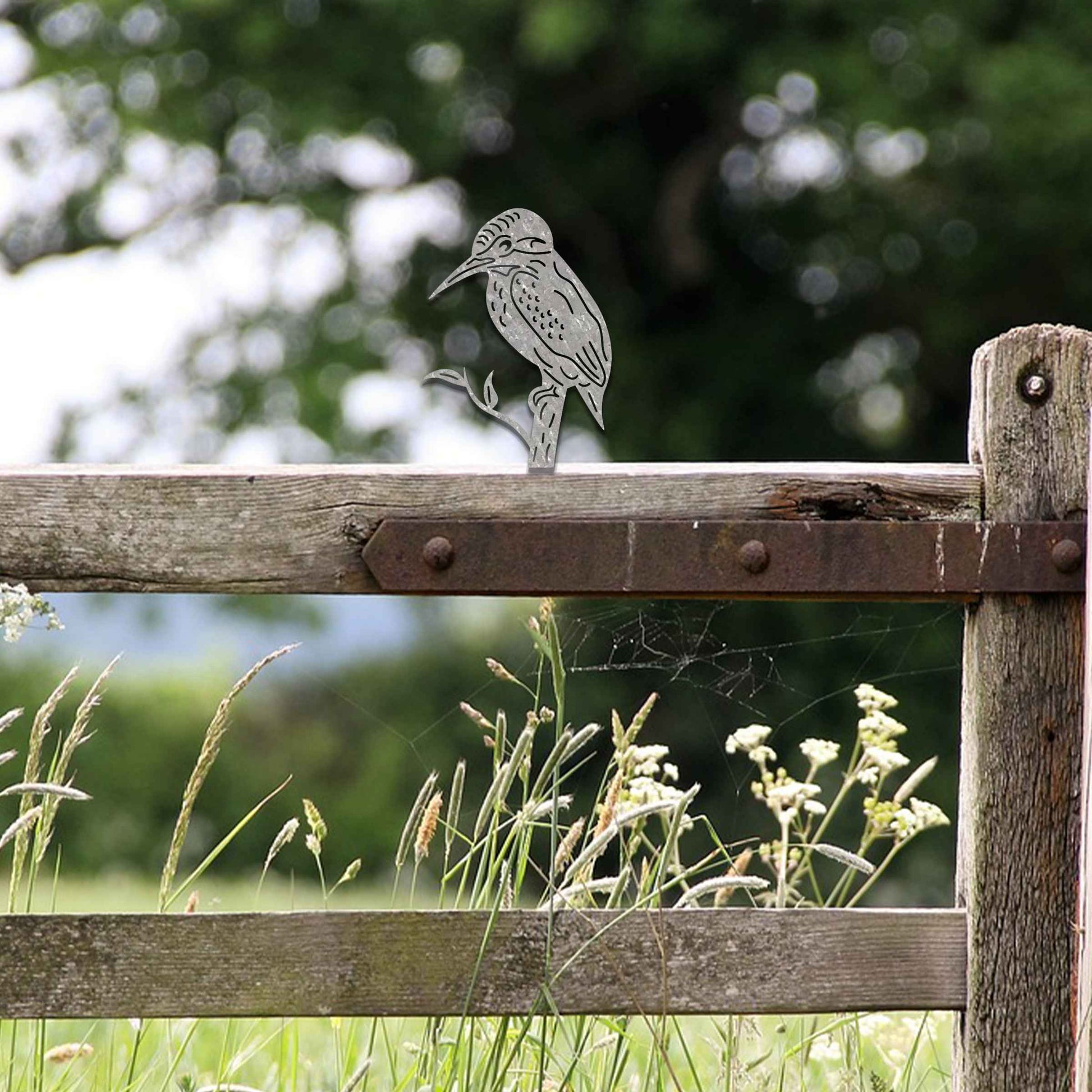 Metal garden decoration featuring a kingfisher silhouette perched on a branch, crafted with a rustic finish, designed to sit atop fences or garden posts, adding a natural and artistic accent to outdoor spaces.
