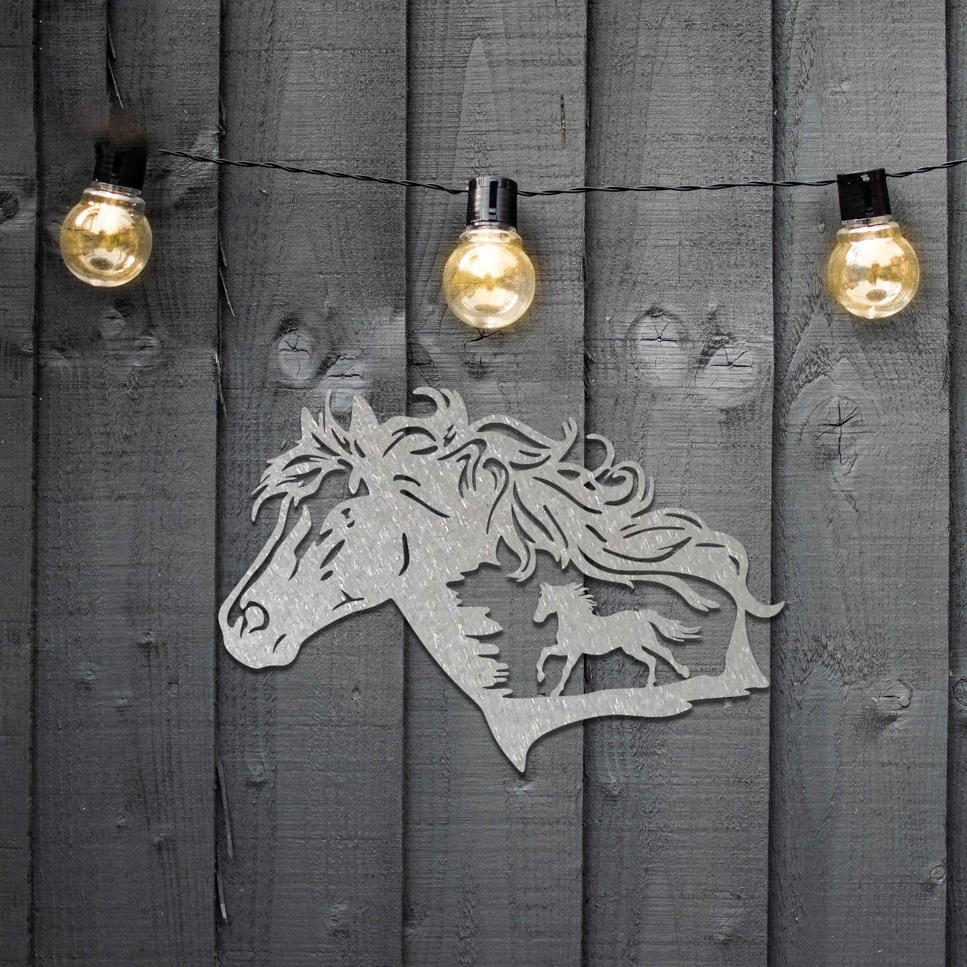 Metal wall decoration featuring a horse head silhouette with flowing mane details and a smaller horse figure within, crafted with intricate cutouts and a rustic finish, adding a majestic and artistic touch to indoor or outdoor spaces.