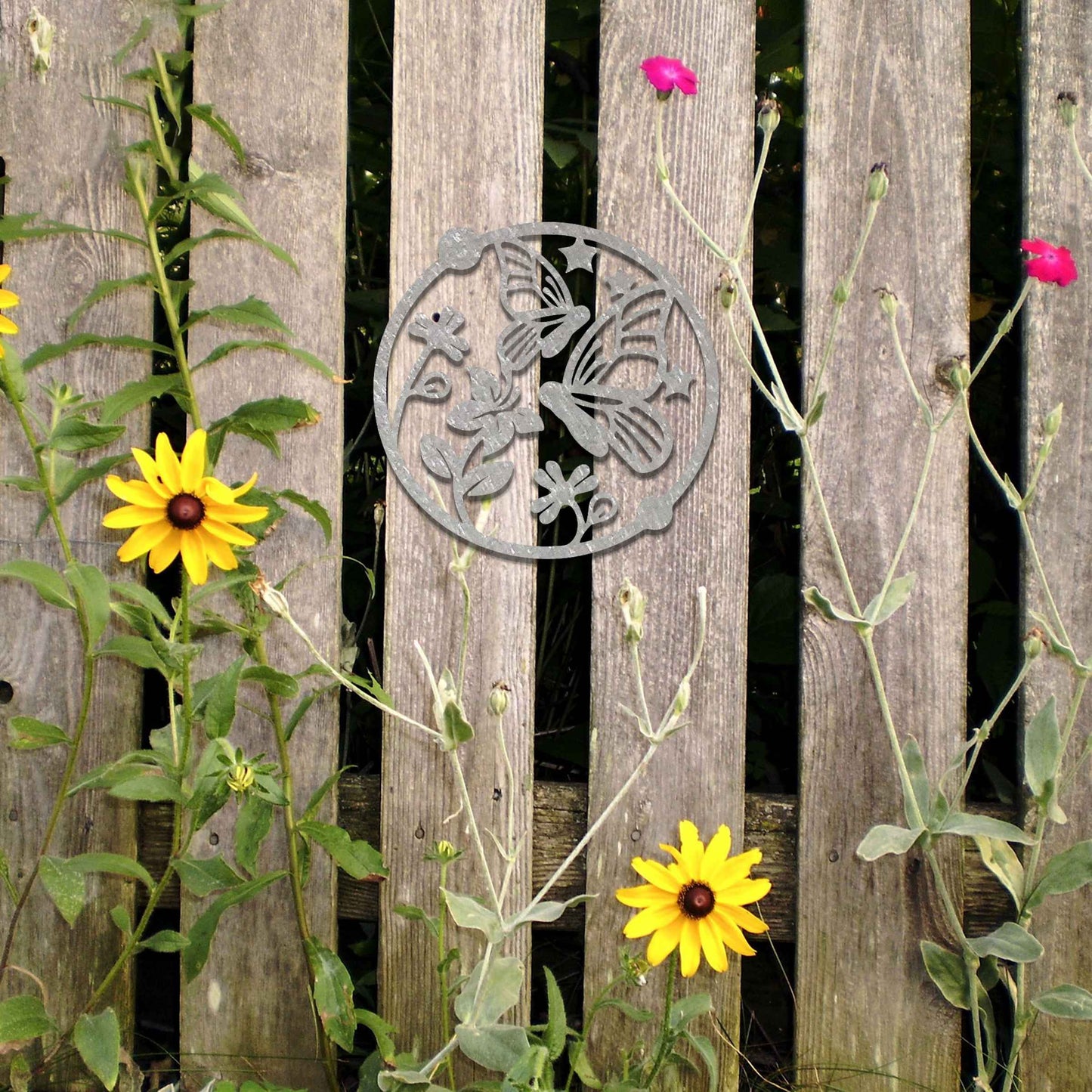 Metal garden decoration featuring a circular design with butterflies, flowers, and stars, crafted with a rustic finish, adding a whimsical and nature-inspired charm to outdoor walls or fences.