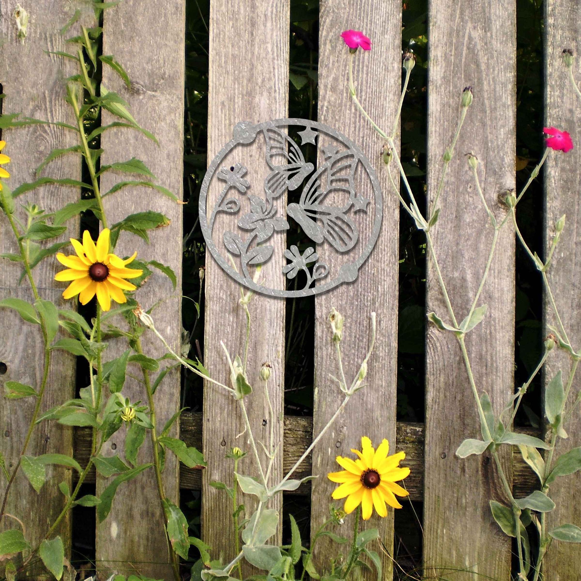 Metal garden decoration featuring a circular design with butterflies, flowers, and stars, crafted with a rustic finish, adding a whimsical and nature-inspired charm to outdoor walls or fences.