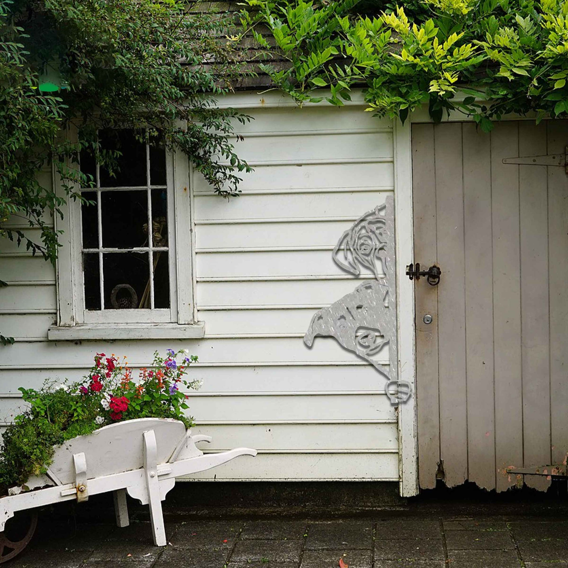 This image features a playful dog peeking through a gate, captured in a rusted finish. Its curious expression brings a whimsical touch to the surroundings, creating an inviting, charming atmosphere for any garden or outdoor space.