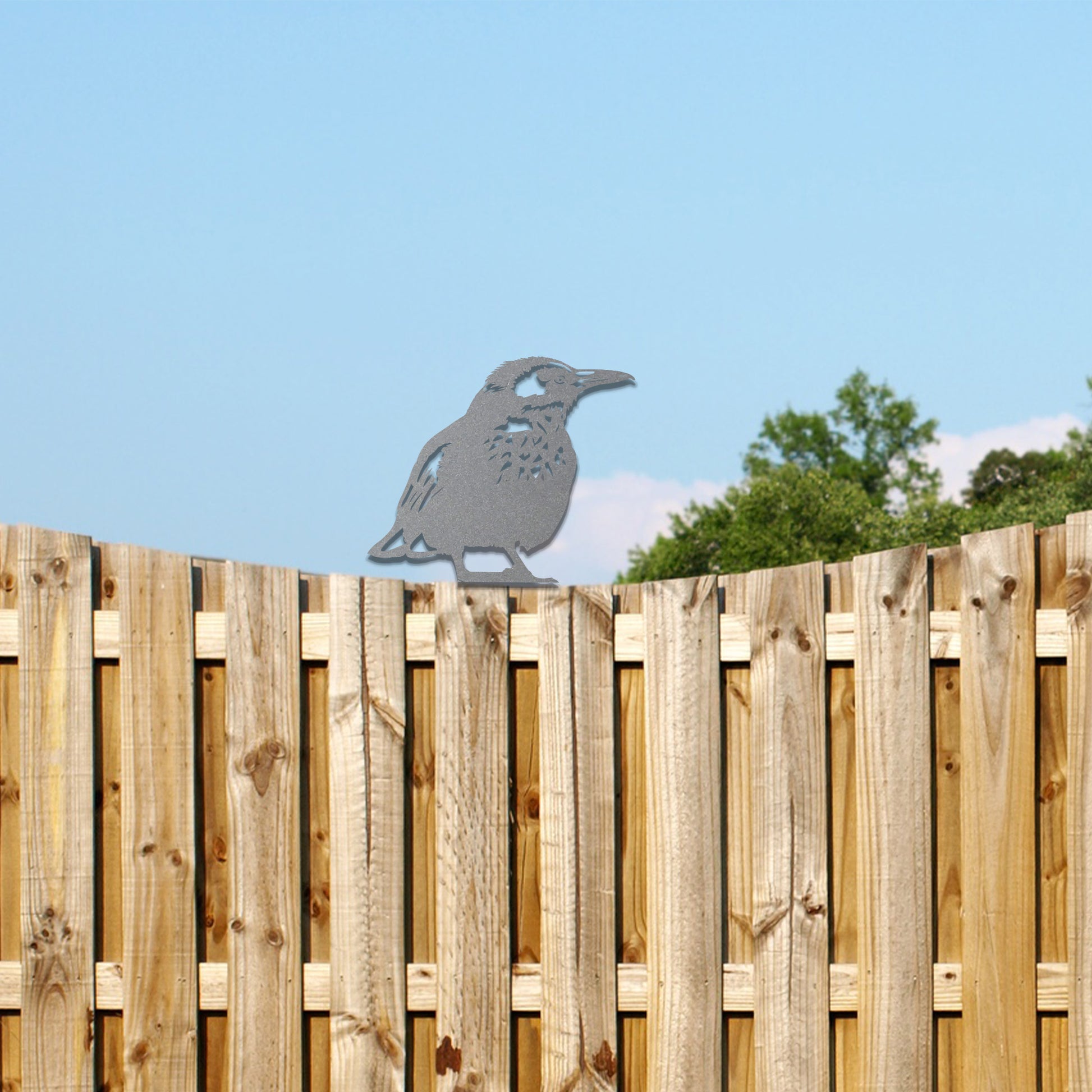 Metal wall art of a bird perched on a wooden fence post, featuring detailed wing and feather patterns. The bird is in a relaxed pose, surrounded by sunflowers, showcasing nature's beauty.