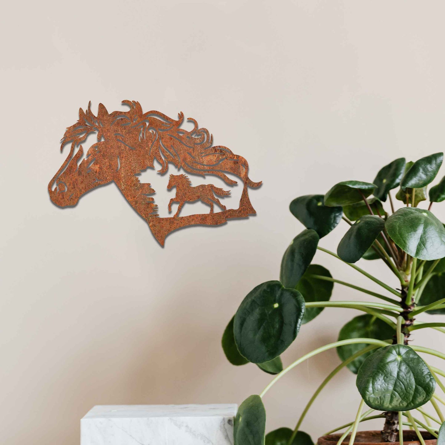 Metal wall decoration featuring a horse head silhouette with flowing mane details and a smaller horse figure within, crafted with intricate cutouts and a rustic finish, adding a majestic and artistic touch to indoor or outdoor spaces.