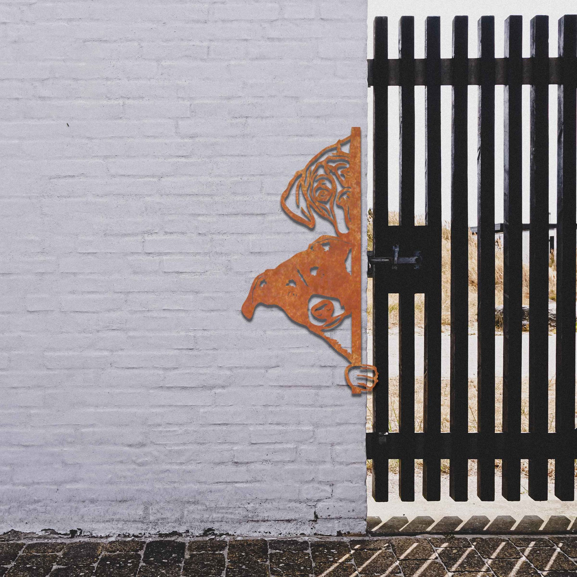 This image features a playful dog peeking through a gate, captured in a rusted finish. Its curious expression brings a whimsical touch to the surroundings, creating an inviting, charming atmosphere for any garden or outdoor space.
