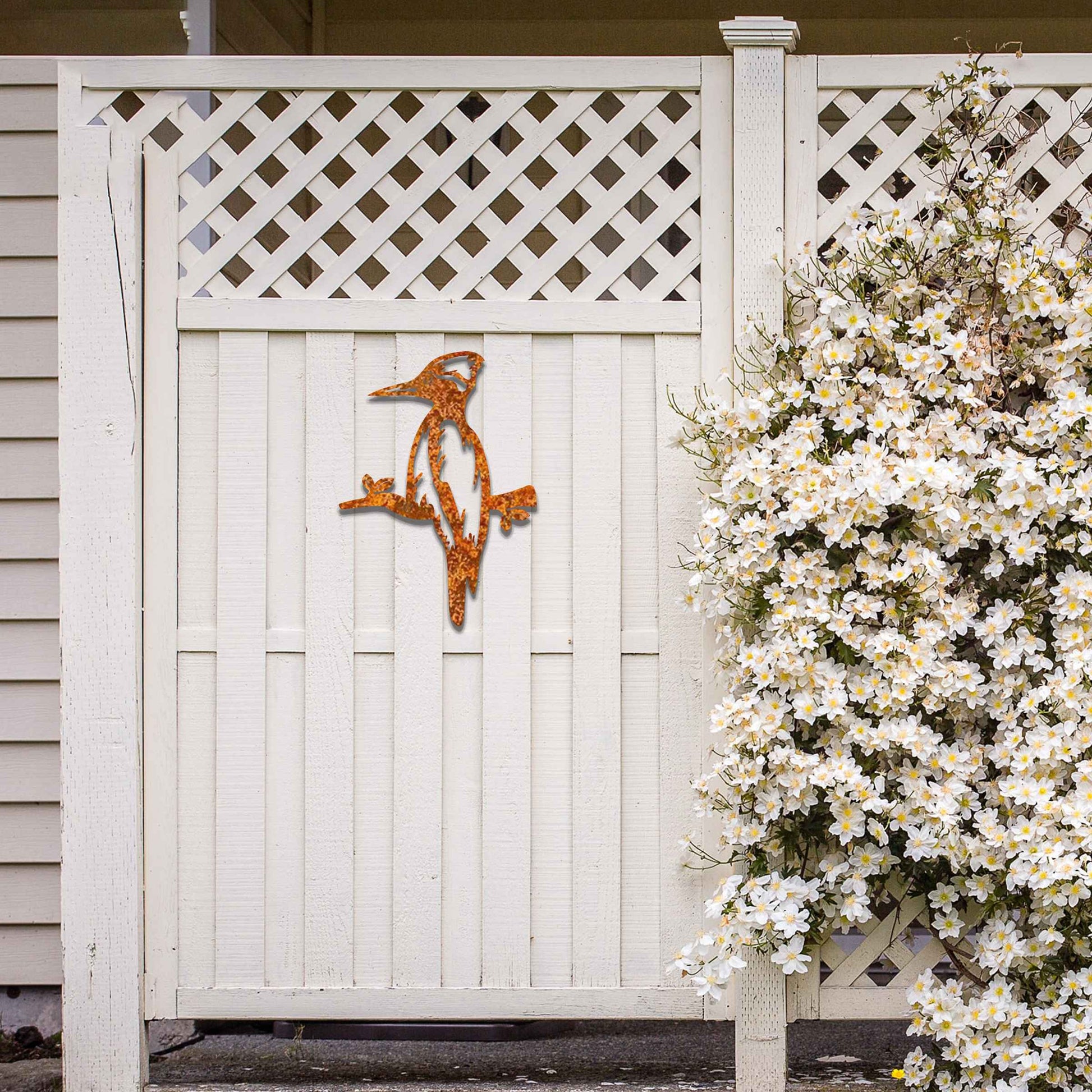 Metal garden decoration featuring a woodpecker perched on a branch, crafted with a rustic finish, adding a touch of nature-inspired charm and elegance to outdoor walls or garden settings.