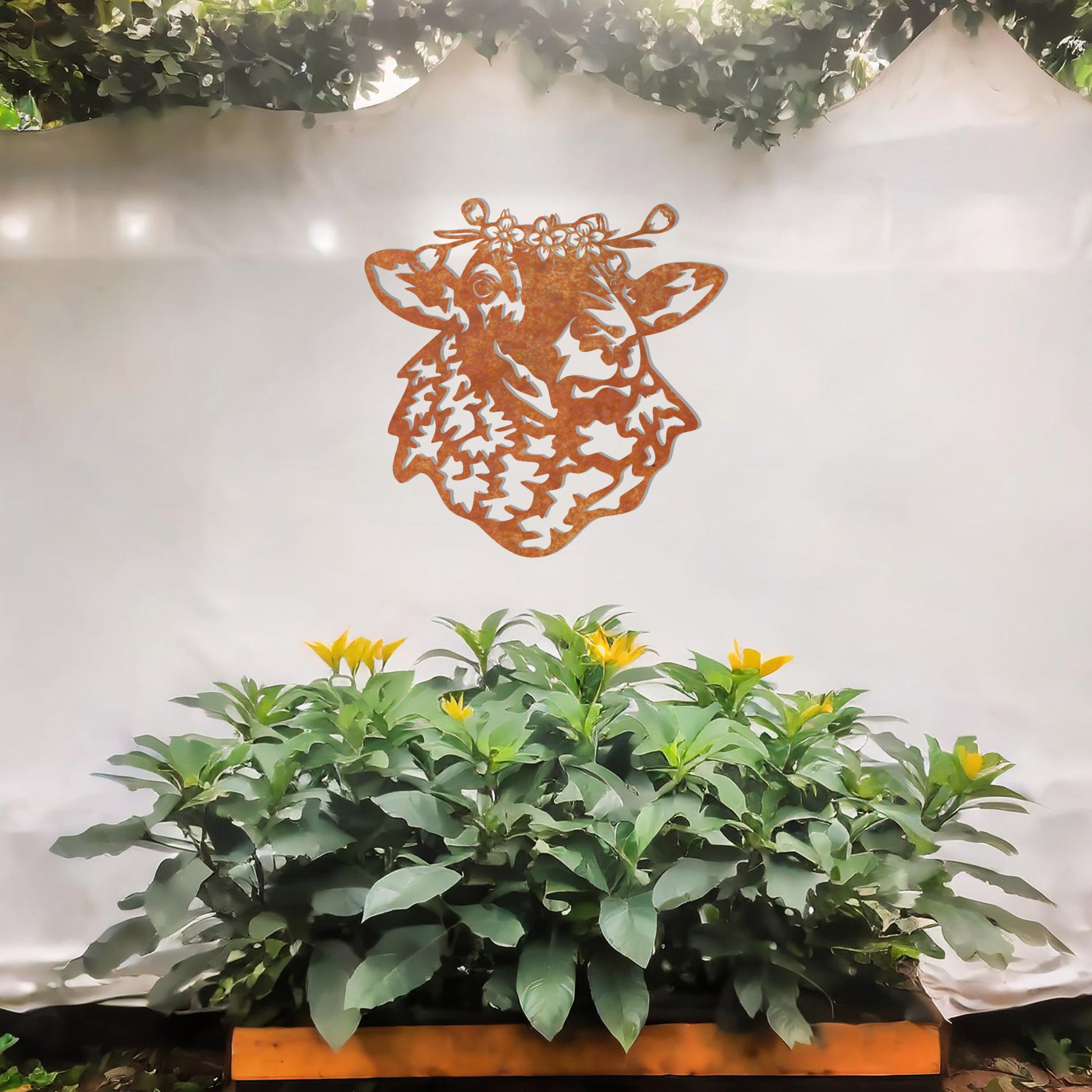 A metal wall art piece depicting a sheep adorned with a floral crown, exuding rustic charm and elegance. This intricate design brings a touch of countryside serenity to any modern or natural setting, complemented by its leafy surroundings.