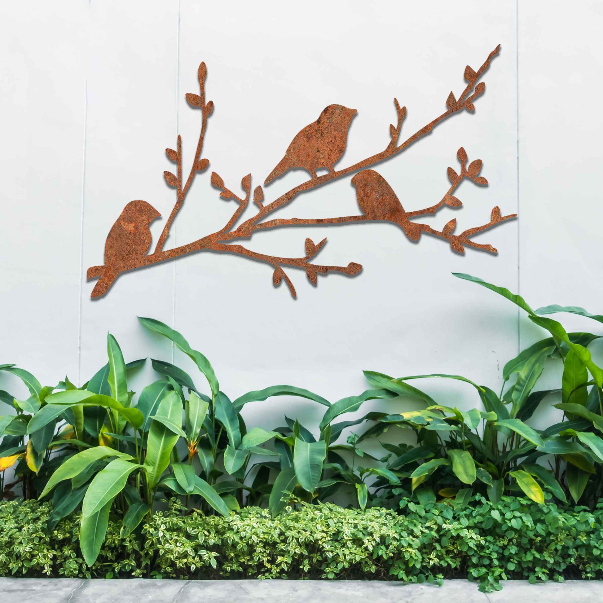 Metal garden decoration featuring three birds perched on a leafy branch, crafted with intricate cutout details and a rustic finish, adding a charming and natural touch to outdoor walls or garden spaces.