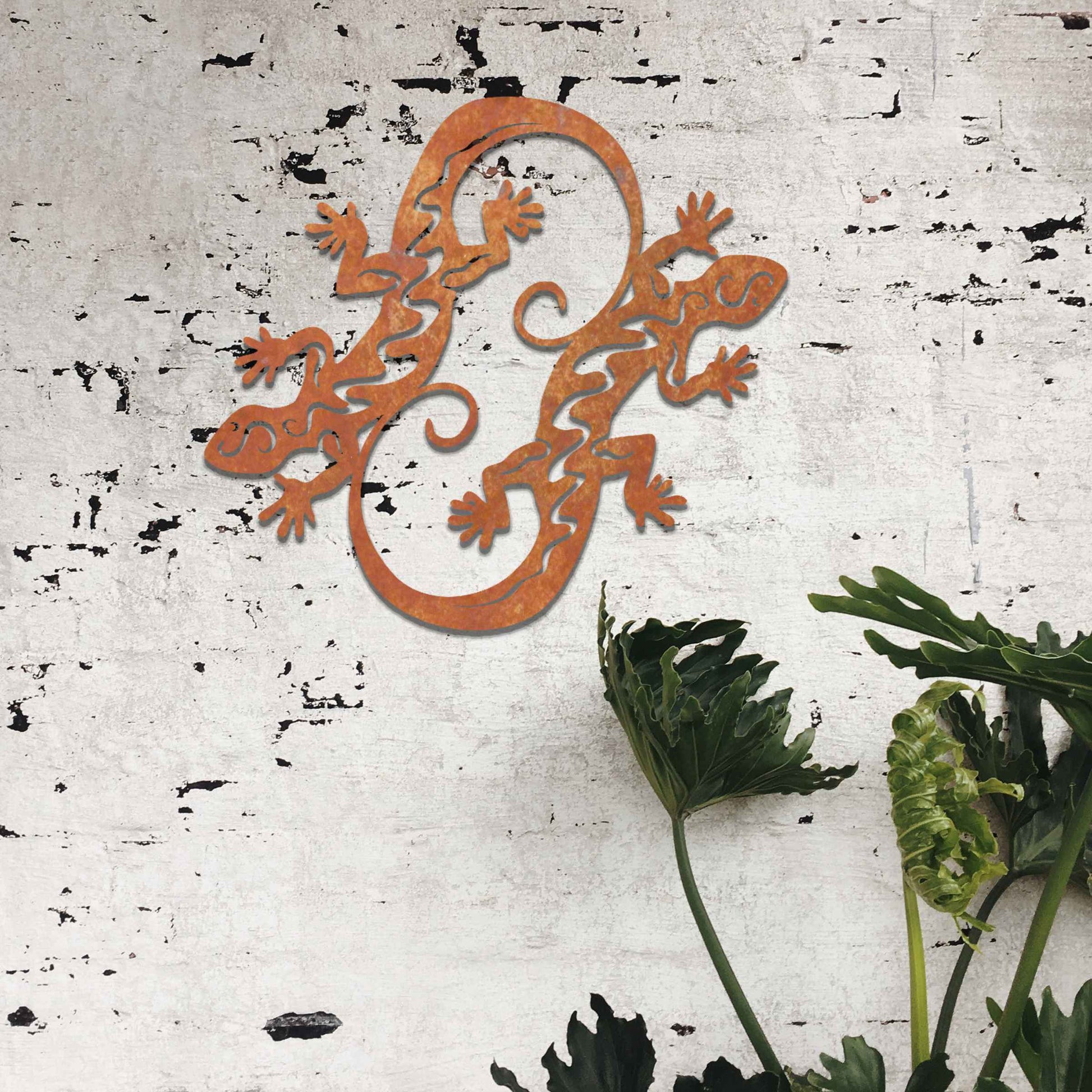 Metal wall decoration featuring two intertwined gecko designs with flowing and curved patterns, adding a dynamic and modern artistic touch to indoor spaces, displayed on a neutral wall within contemporary decor.