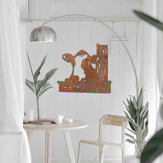 The design features a cow's head peeking over a wooden fence. The cow is drawn with distinct lines, giving it a playful and curious look. The stylized wooden posts complement the cow’s design, adding depth and structure.