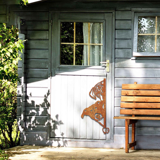 This image features a playful dog peeking through a gate, captured in a rusted finish. Its curious expression brings a whimsical touch to the surroundings, creating an inviting, charming atmosphere for any garden or outdoor space.
