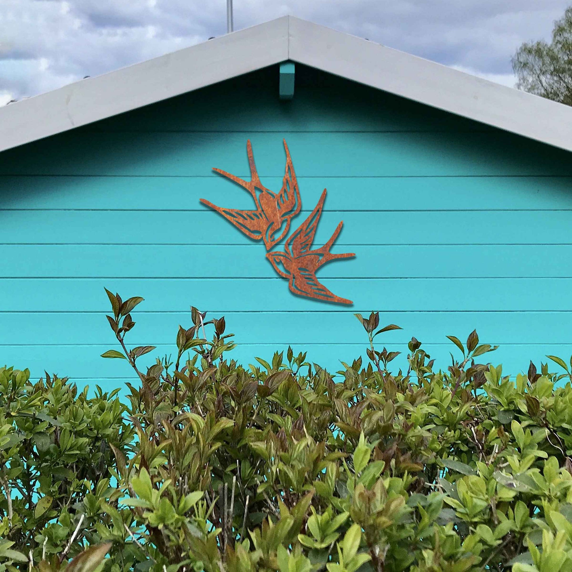 Metal garden decoration featuring a pair of swallows in flight, crafted with intricate detailing and a rustic finish, adding a graceful and timeless charm to outdoor walls or garden spaces.