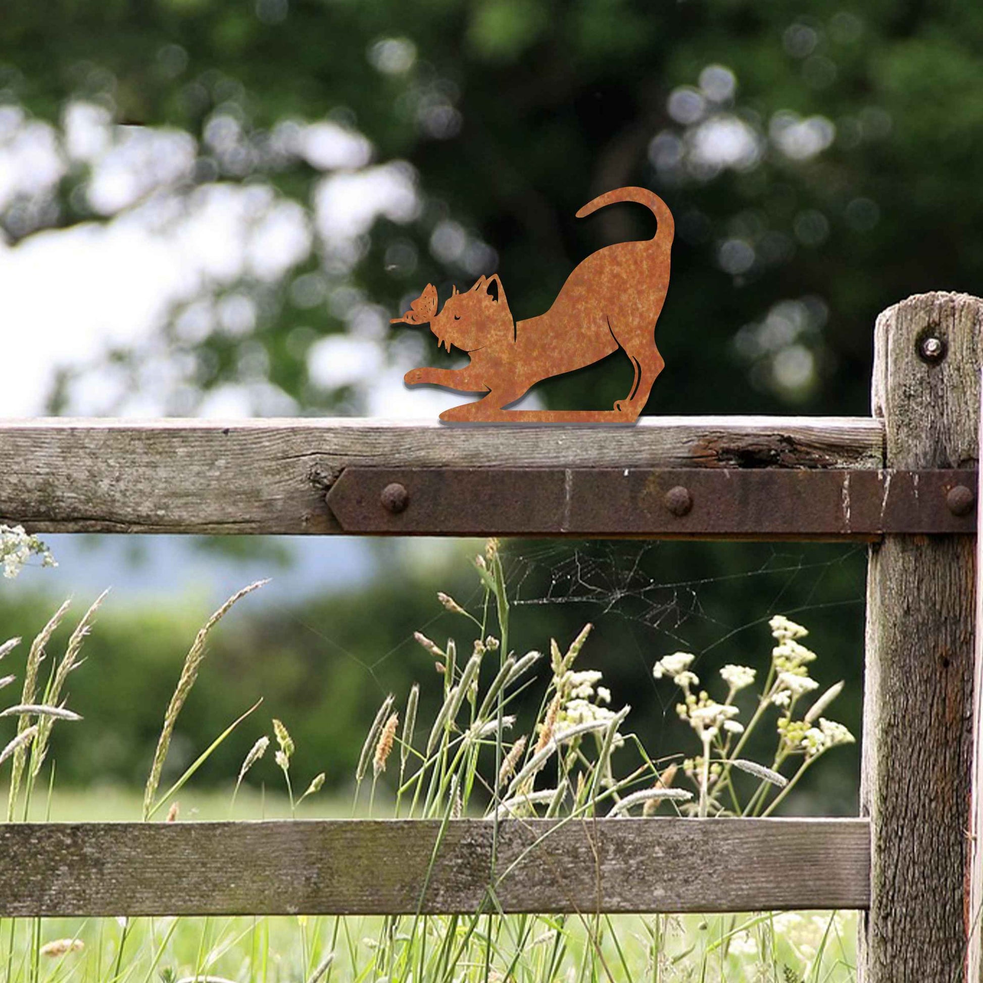 Metal garden decoration featuring a playful stretching cat silhouette with a rustic finish, designed to sit atop fences or posts, adding a whimsical and charming touch to outdoor garden settings.