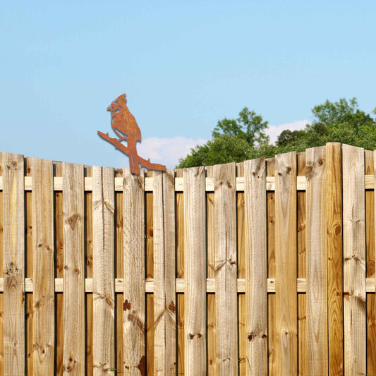 Metal garden decoration featuring a cardinal perched on a branch with intricate cutout details and a rustic finish, designed to enhance wooden fences or gates, adding a striking and natural accent to outdoor spaces.