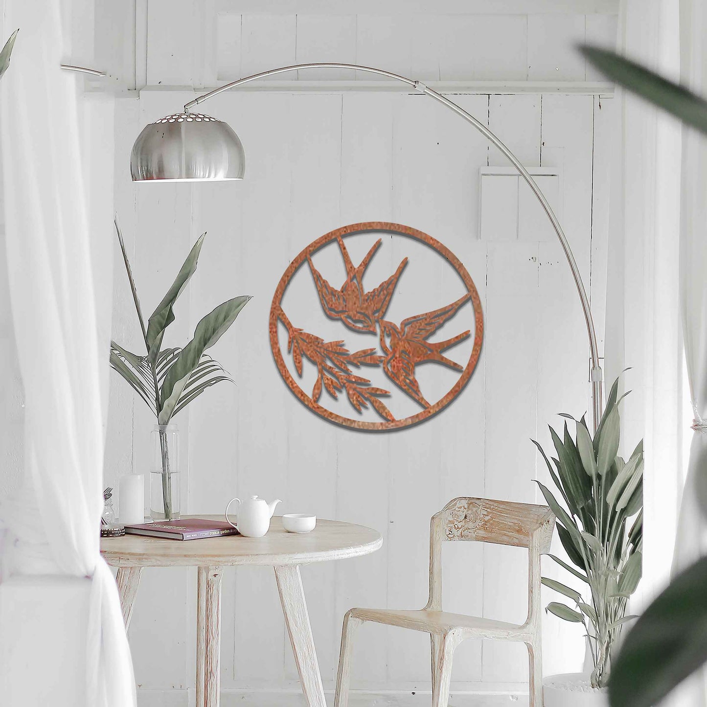 Metal garden decoration featuring two swallows in flight within a circular frame, accented by delicate branch details, combining nature-inspired elegance and craftsmanship to enhance outdoor or indoor spaces.