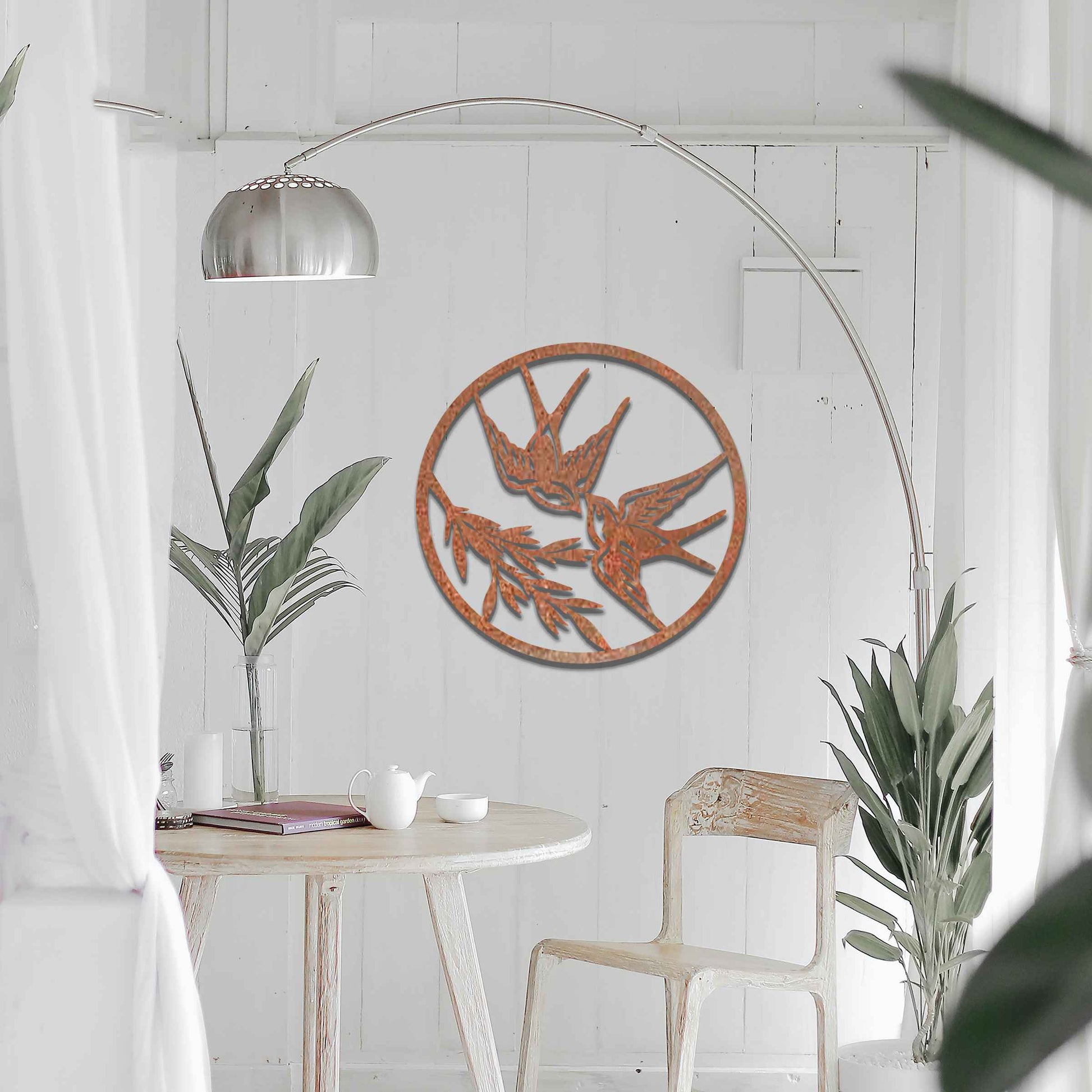 Metal garden decoration featuring two swallows in flight within a circular frame, accented by delicate branch details, combining nature-inspired elegance and craftsmanship to enhance outdoor or indoor spaces.
