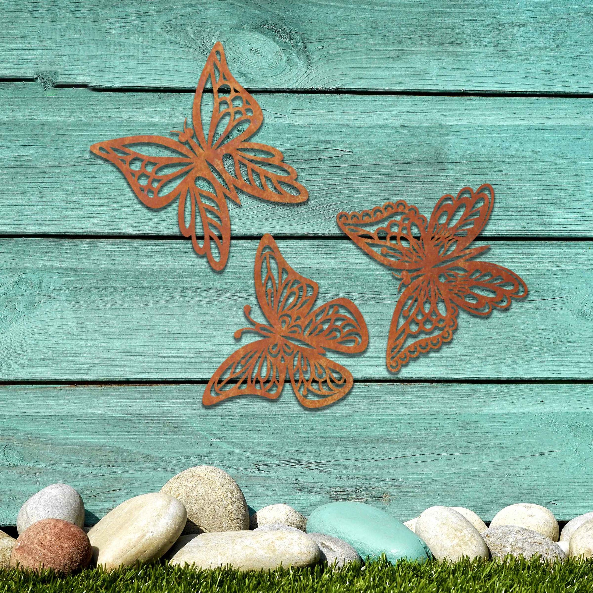 Set of metal garden decorations featuring three intricately designed butterflies with a rustic finish, adding a graceful and nature-inspired aesthetic to outdoor walls or garden spaces.