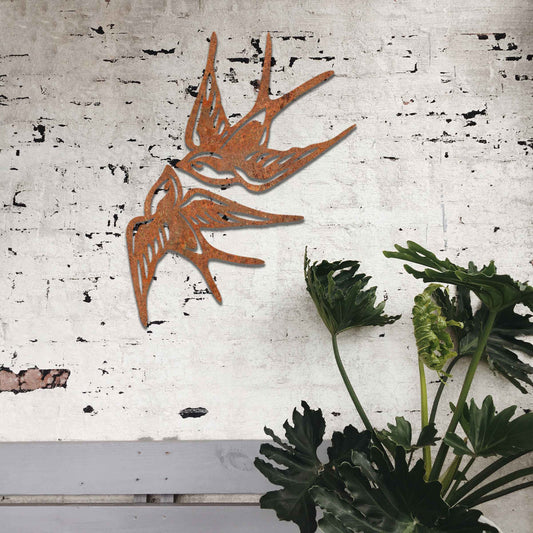 Metal garden decoration featuring a pair of swallows in flight, crafted with intricate detailing and a rustic finish, adding a graceful and timeless charm to outdoor walls or garden spaces.