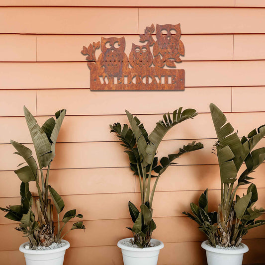 Metal garden decoration featuring three owls perched on a "Welcome" sign with a rustic finish, combining playful charm and warmth to create an inviting accent for outdoor walls, porches, or entryways.