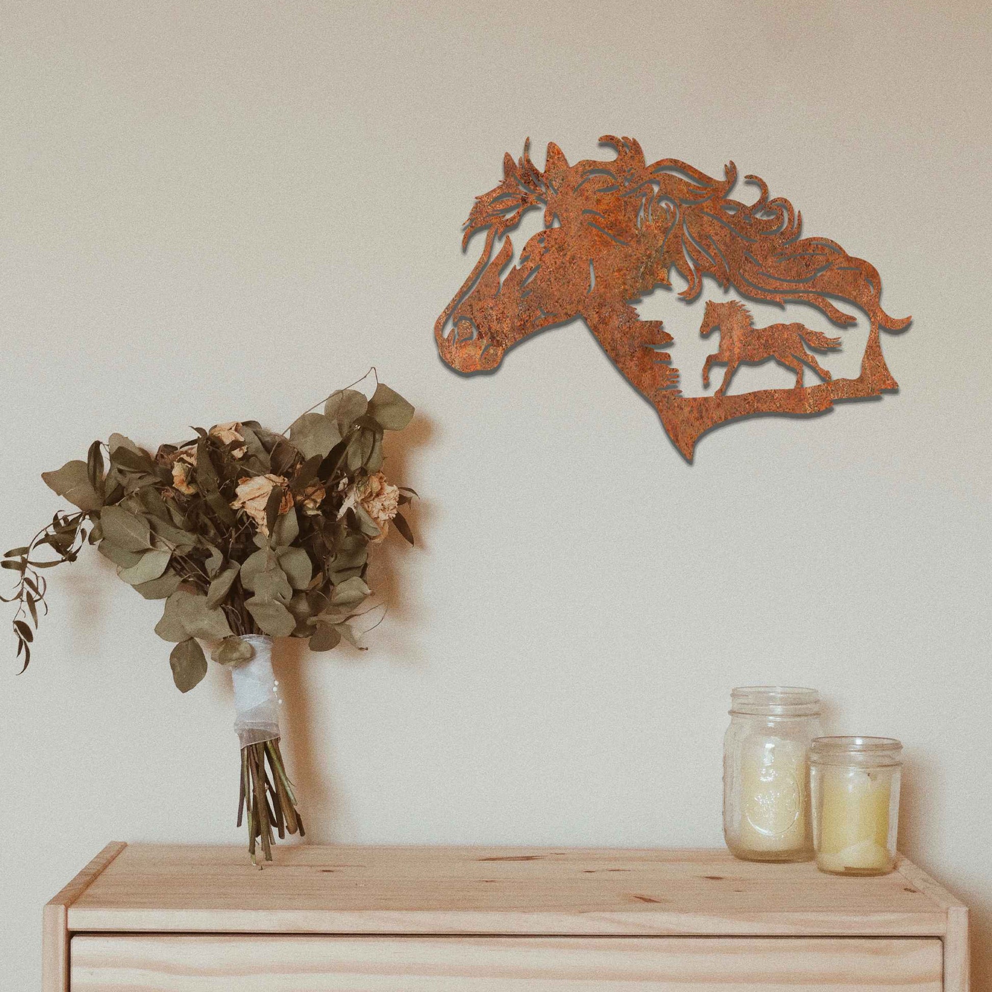 Metal wall decoration featuring a horse head silhouette with flowing mane details and a smaller horse figure within, crafted with intricate cutouts and a rustic finish, adding a majestic and artistic touch to indoor or outdoor spaces.