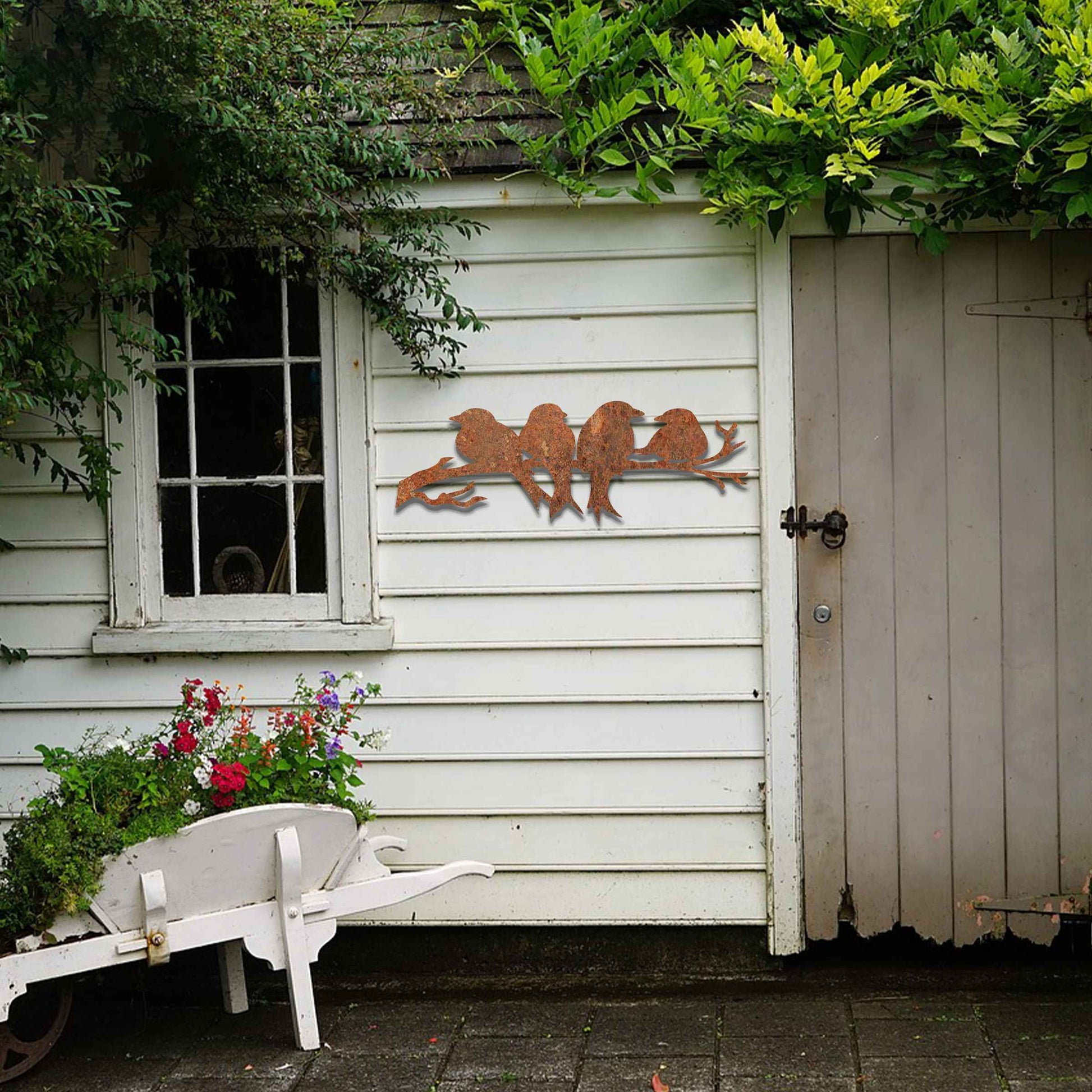Metal garden decoration featuring four birds sitting on a branch, crafted with intricate cutout details and a rustic finish, adding a delightful and natural charm to outdoor walls or garden spaces.
