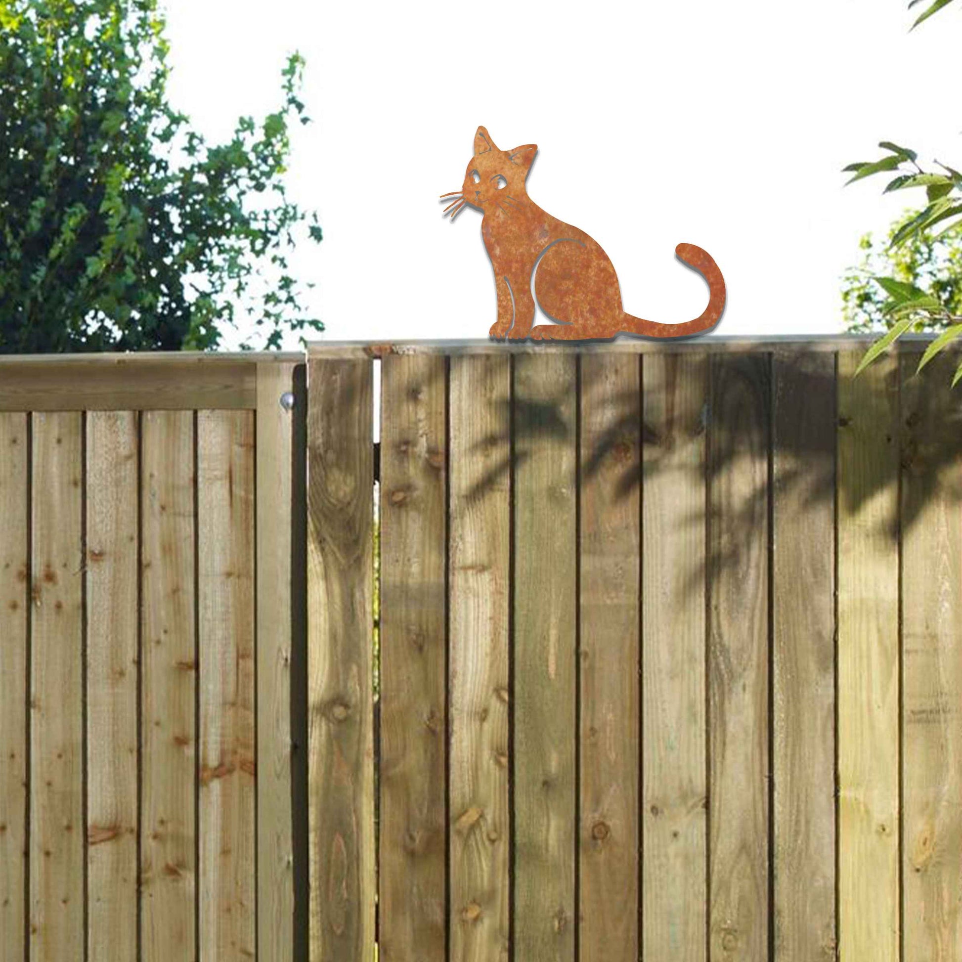 Metal garden decoration featuring a sitting cat silhouette with a rustic finish, designed to adorn fence tops or garden posts, adding a charming and playful touch to outdoor spaces.