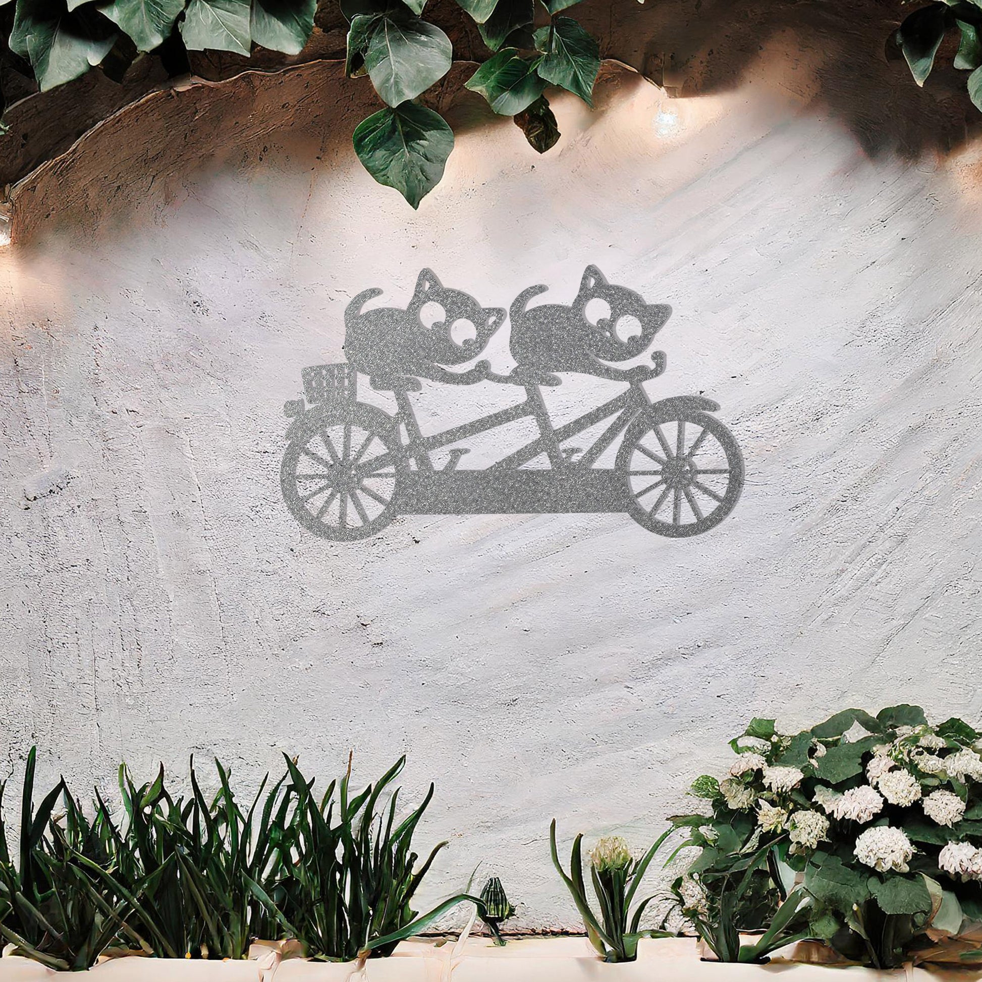 A charming metal wall art design depicting two playful cats riding a tandem bicycle, capturing a whimsical and fun moment with intricate details of the bike and expressive cat figures.