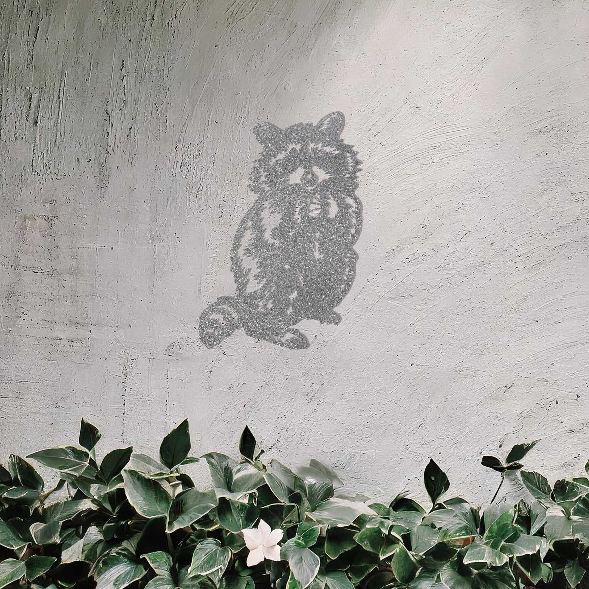 A metal wall art piece featuring a detailed raccoon design, evoking charm and playfulness. This adorable artwork adds a whimsical touch to modern or rustic settings, harmonising beautifully with natural decor elements.