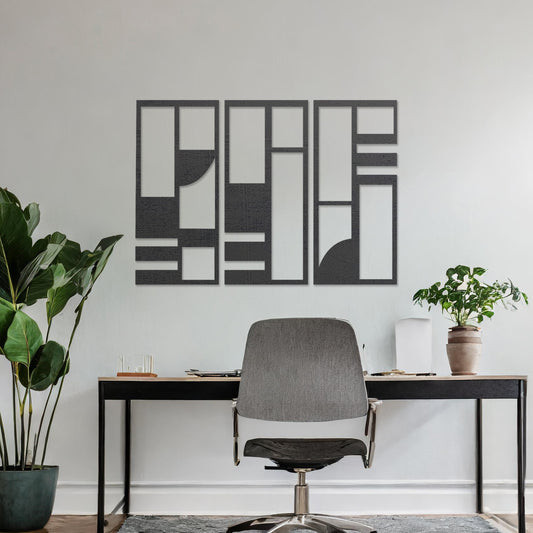 This image displays a modern, abstract triptych wall art piece featuring geometric patterns in dark tones. The artwork is placed above a simple desk setup with a plant and a chair, providing a stylish and minimalistic atmosphere suitable for a contemporary workspace. 