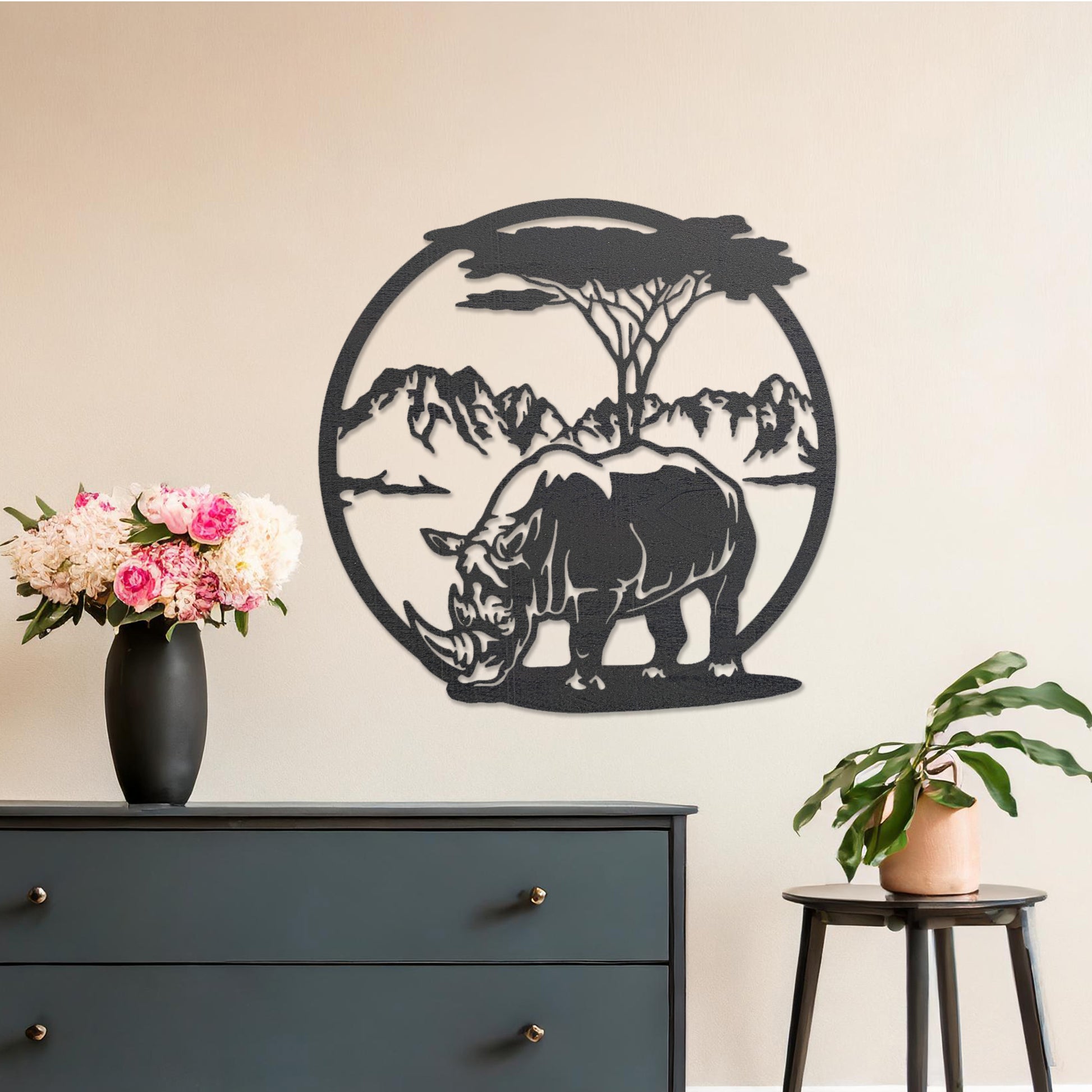 Wooden wall art design featuring a rhinoceros beneath a tree with a mountain backdrop, framed in a circular shape, placed on a neutral wall within modern room decor. The design captures the majesty of wildlife in a serene landscape.