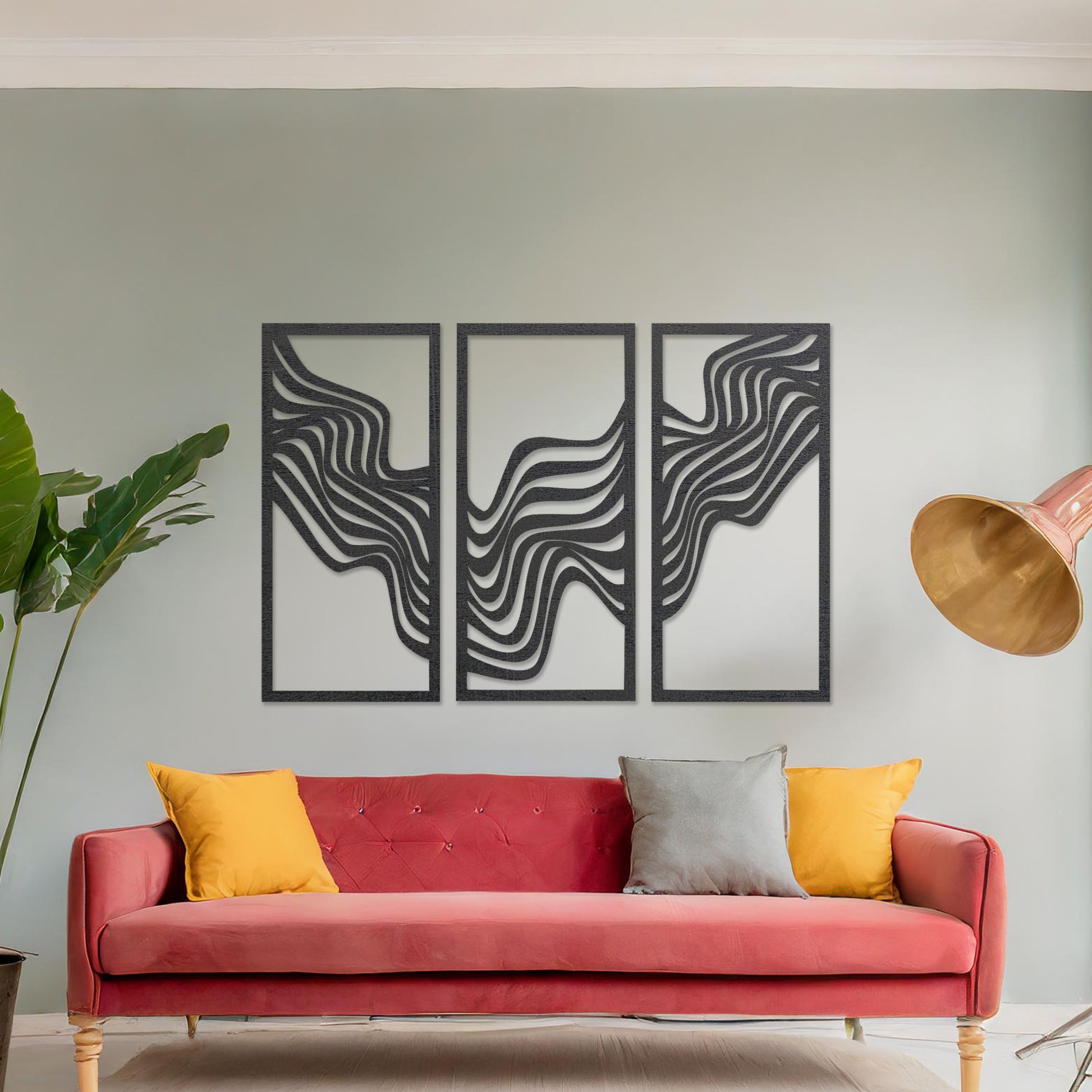 This image displays a modern triptych wall art design featuring flowing wave-like lines. The abstract patterns create a dynamic and visually appealing composition, adding an elegant touch to the living room's decor, complemented by a colourful sofa and floor lighting.
