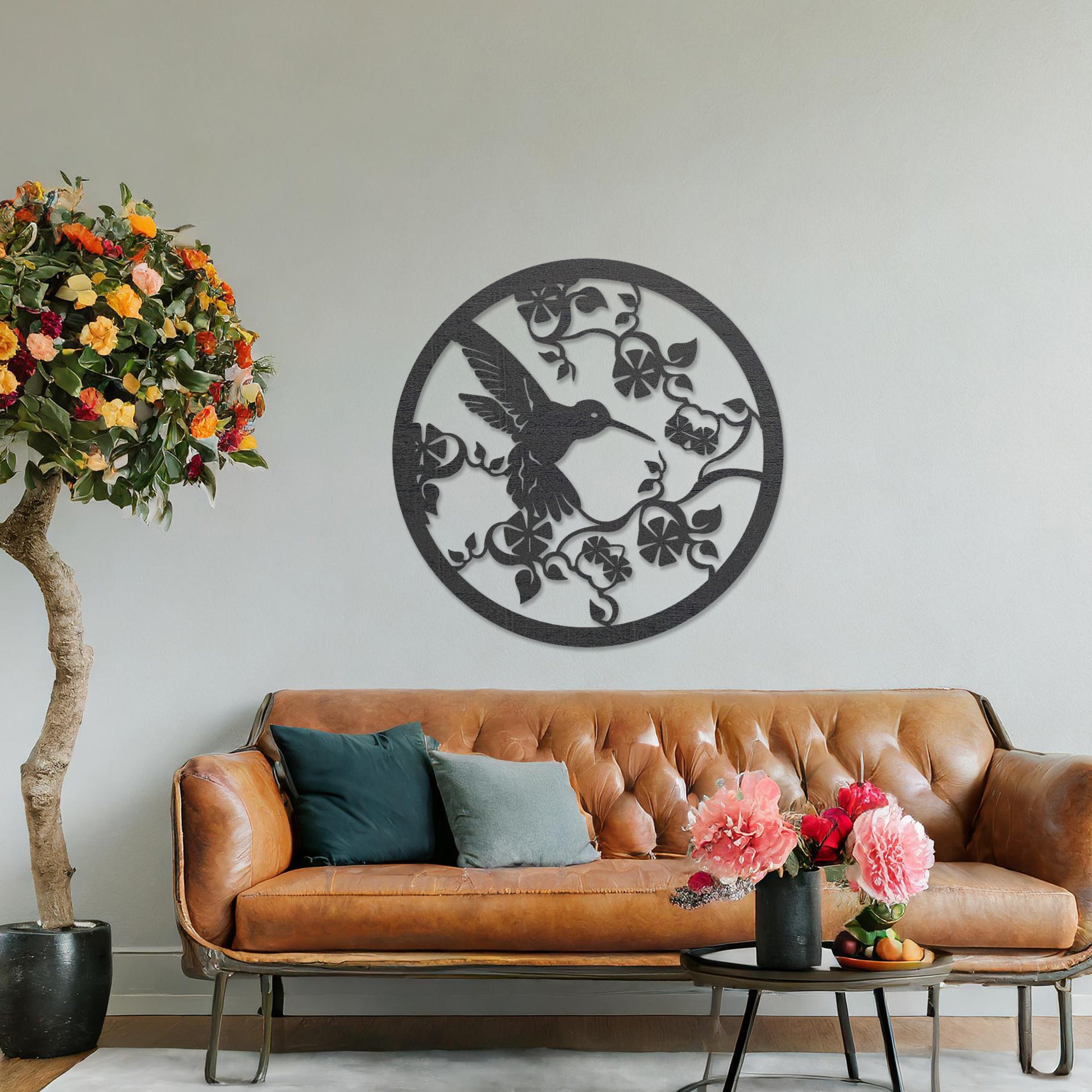 Wooden wall art design featuring a hummingbird amidst flowers and vines, framed in a circular shape, placed on a neutral wall within modern room decor. The design captures the elegance of nature with intricate details.