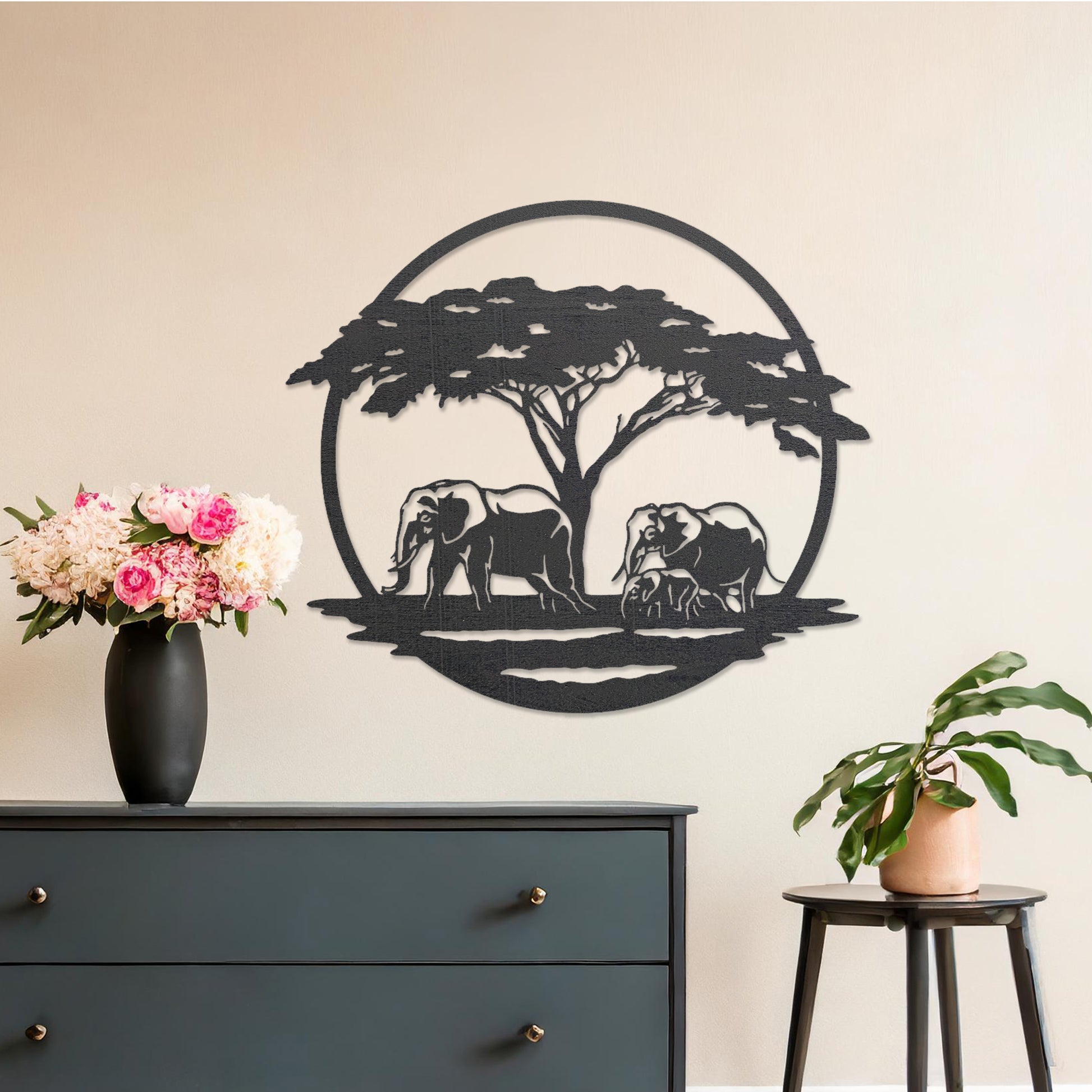 Wooden wall art design featuring two elephants under a tree, framed in a circular shape, placed on a neutral wall within modern room decor. The design evokes a sense of tranquility and nature with its detailed depiction of wildlife.