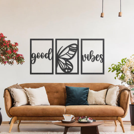 Wooden wall art featuring a three-panel design with the phrase "good vibes" and a butterfly motif in the centre. The artwork is placed on a neutral wall in modern room decor, highlighting its uplifting design.