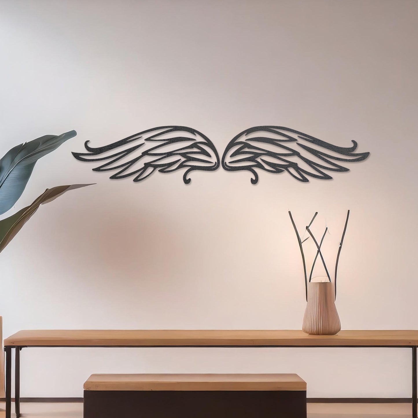Wall art featuring a pair of intricately designed angel wings with flowing lines and graceful curves. The piece is displayed on a neutral wall within modern decor, adding a symbolic and elegant touch to the setting.