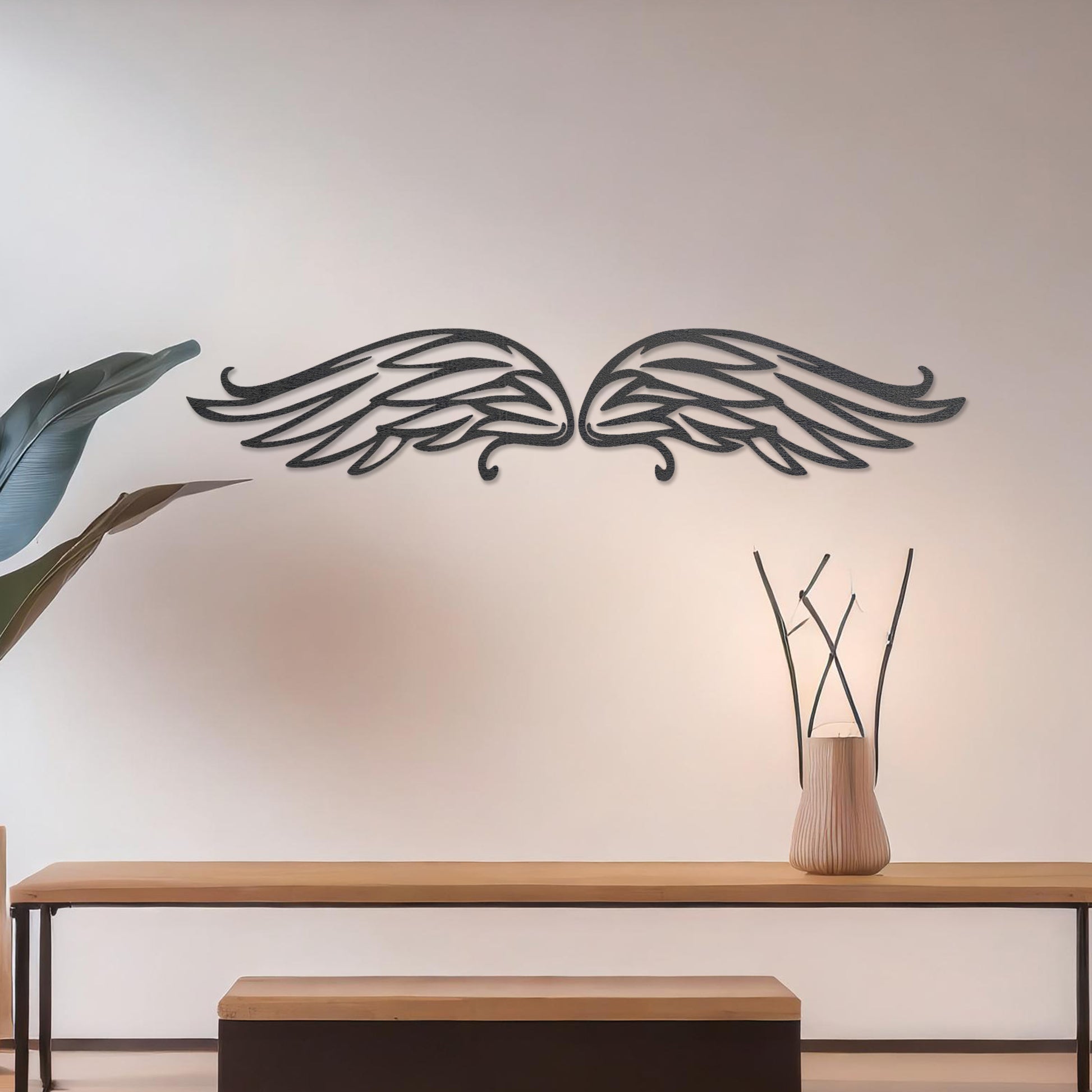 Wall art featuring a pair of intricately designed angel wings with flowing lines and graceful curves. The piece is displayed on a neutral wall within modern decor, adding a symbolic and elegant touch to the setting.