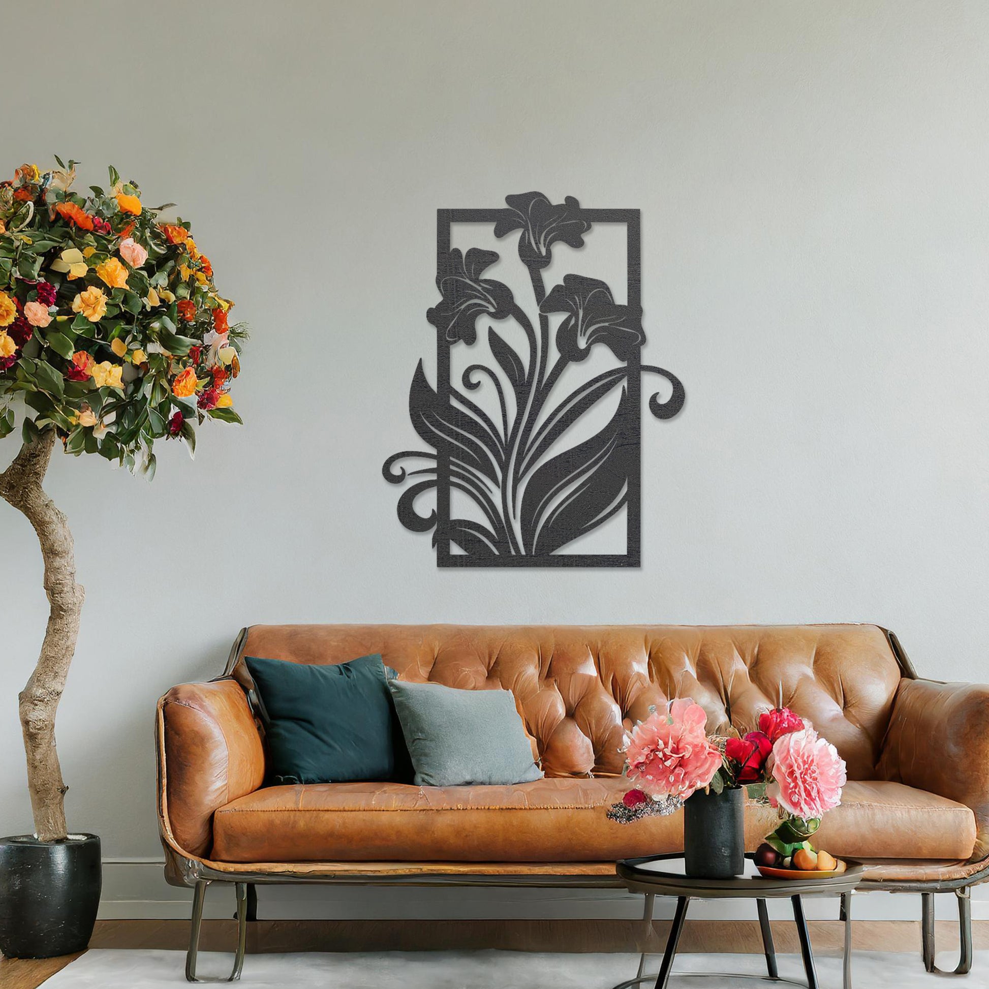 Wall art featuring an elegant floral design with three blooming lilies and flowing leaves enclosed in a rectangular frame. The piece is displayed on a neutral wall within modern room decor, adding a graceful and artistic touch to the setting.
