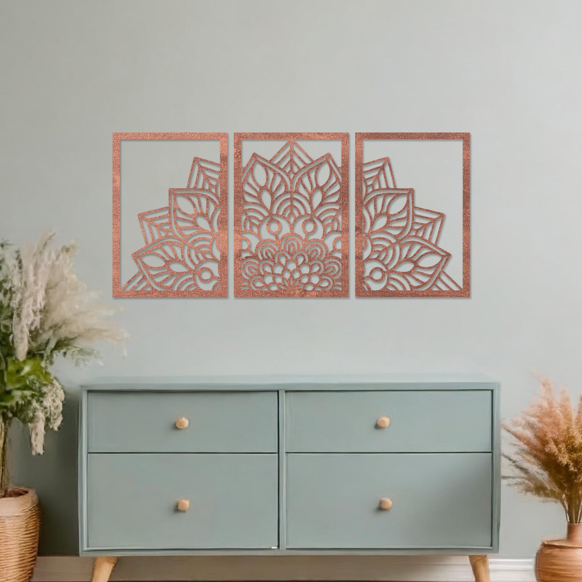 Wall art featuring a triptych design with an intricate mandala pattern spread across three panels. The artwork is displayed on a neutral wall within modern room decor, adding a harmonious and decorative touch to the setting.