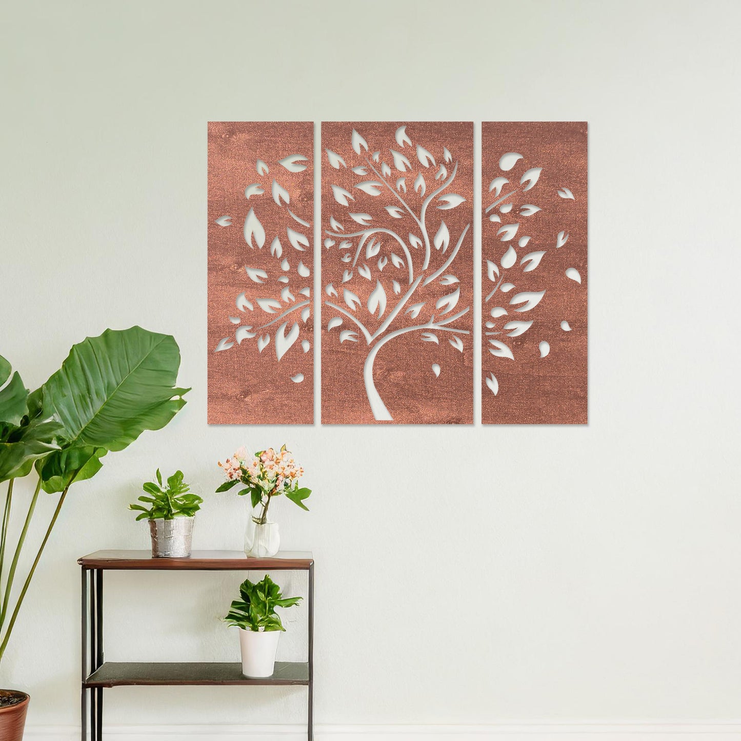 Wooden wall art consisting of three panels featuring a flowing tree design with scattered leaves, displayed on a neutral wall within modern room decor, emphasising its elegant and natural aesthetic.